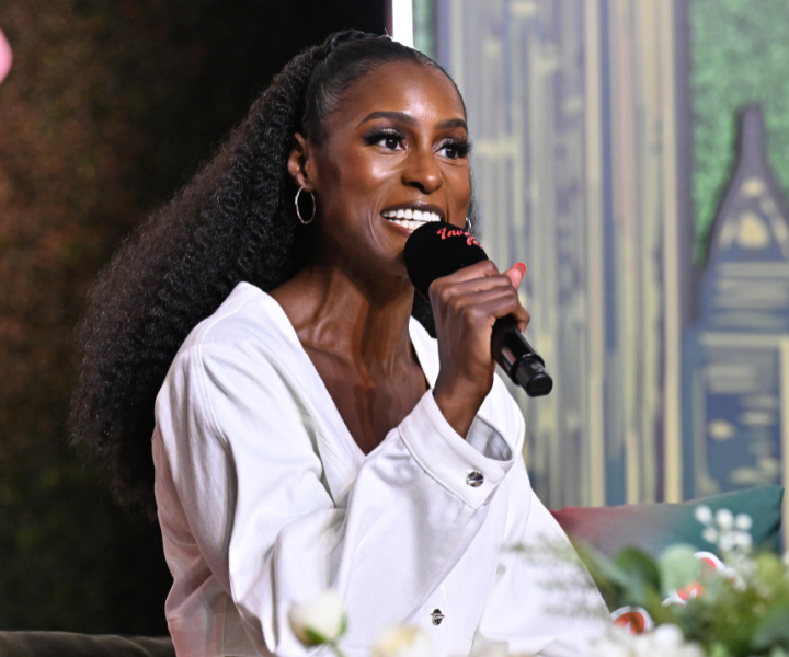 Atriz e produtora veste camisa branca de algodão com modelagem ampla, cabelos presos em rabo volumoso.