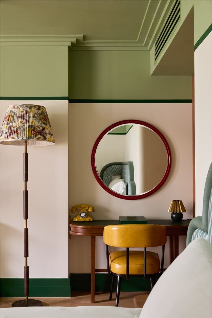 Decoração neo déco com móveis em madeira curva, poltrona em couro mostarda, espelho redondo vermelho e tons verde e bege