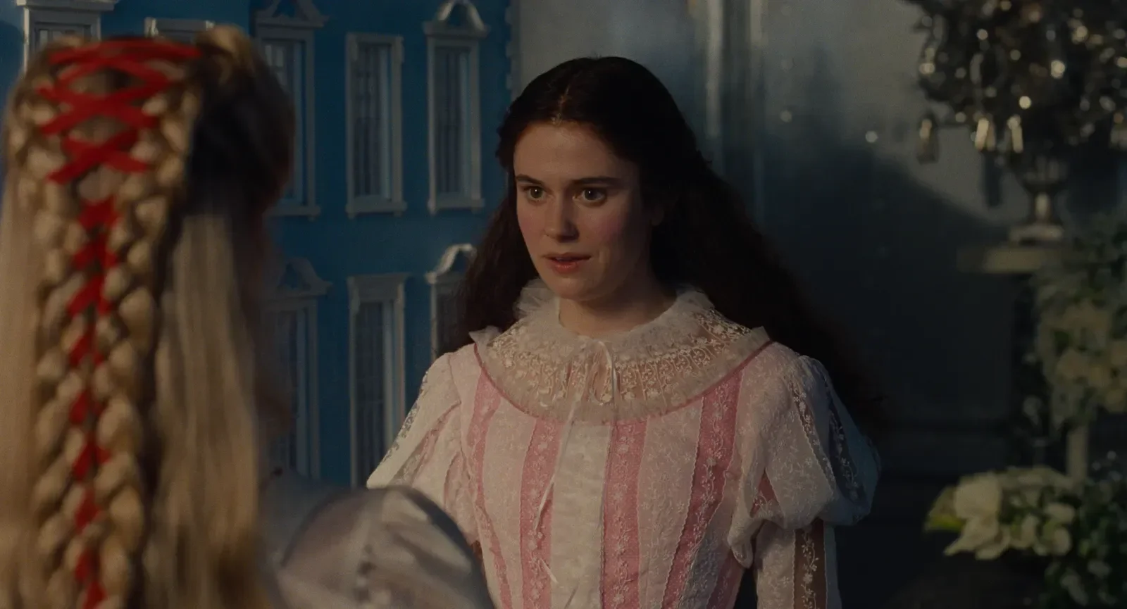 Personagem de O Morro dos Ventos Uivantes usa vestido rosa e branco com renda e babados, expressando surpresa