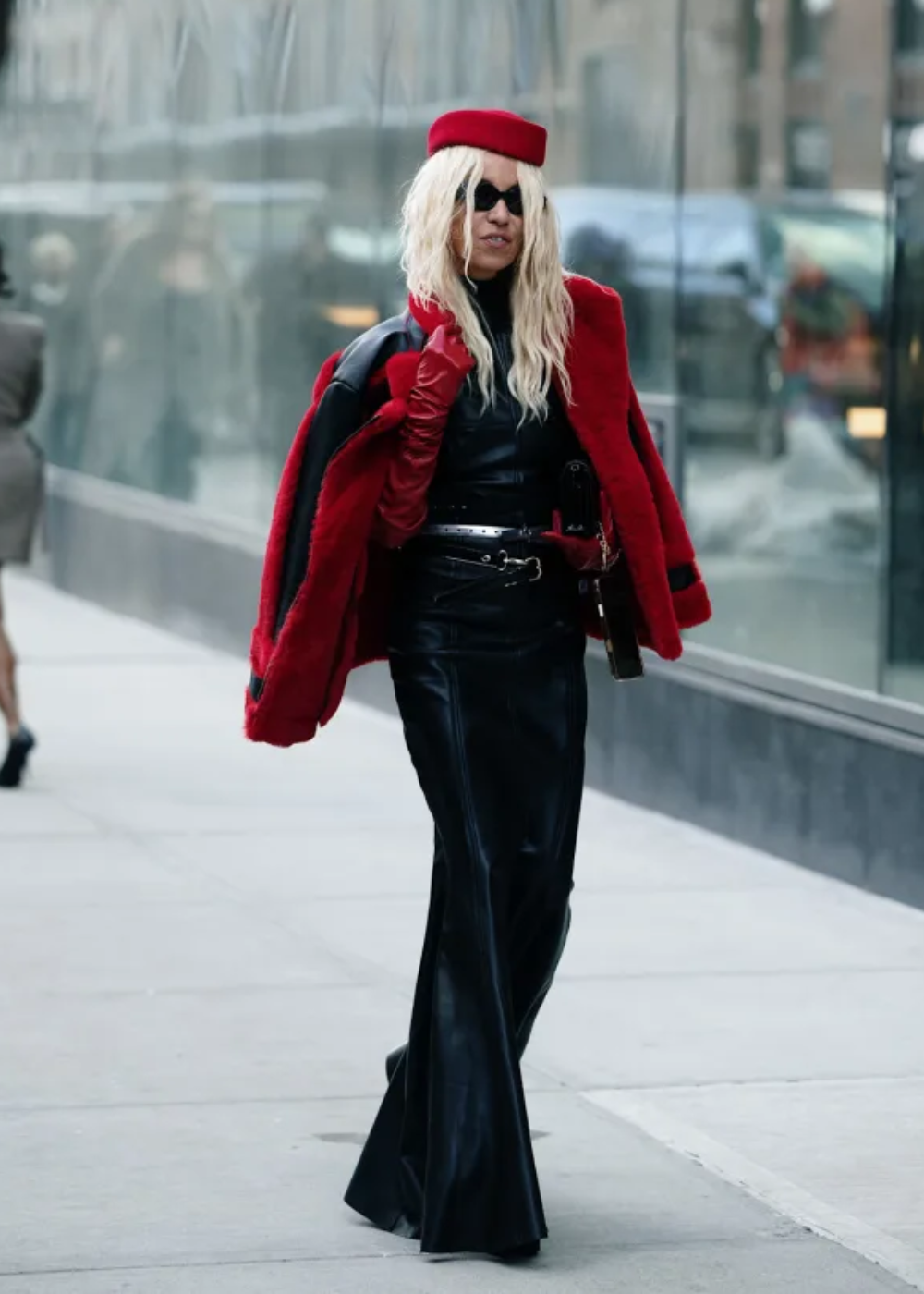 Modelo caminha confiante usando pillbox hat vermelho em tecido estruturado, casaco e luvas vermelhas.