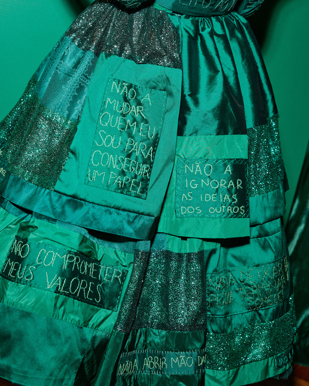 Saia rodada em tons verdes com tecidos variados, incluindo paetês e cetim, exibe mensagens bordadas sobre saber dizer “não”