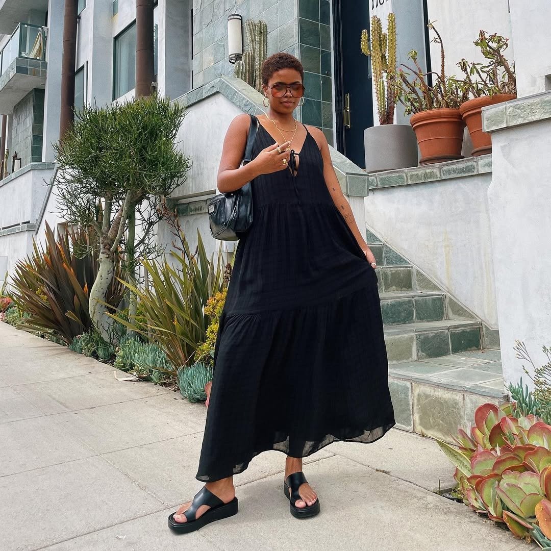 Modelo posa com vestido de verão chique preto, fluido e leve, combinado com vestidos de verão chiques