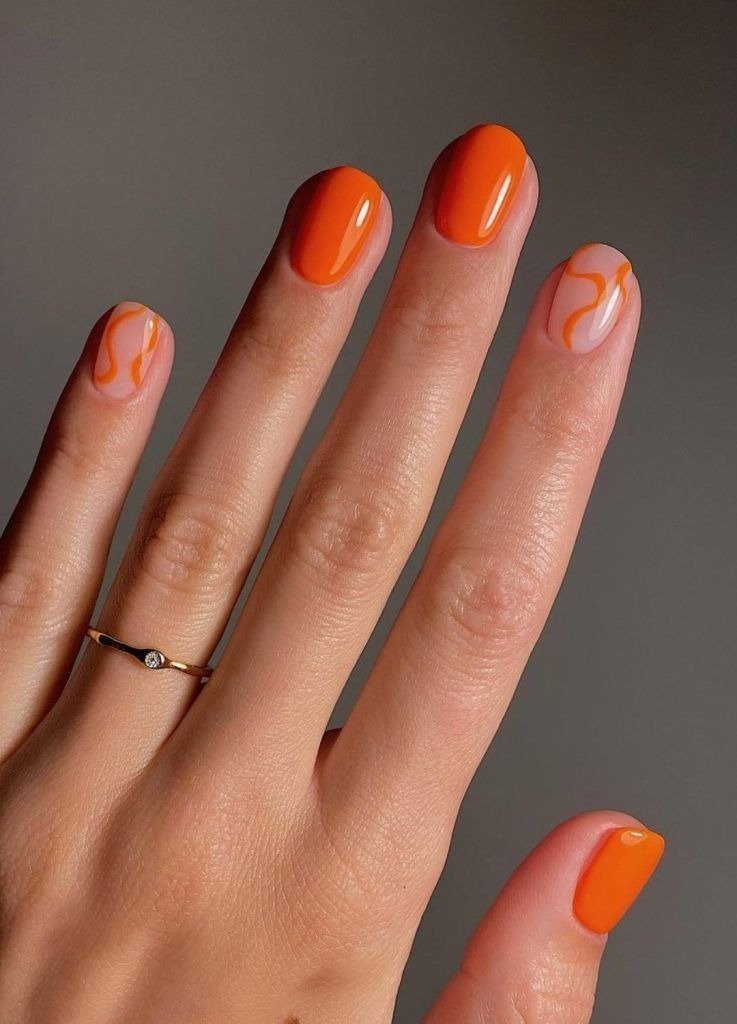 Unhas coloridas da moda em tom laranja vibrante com detalhes abstratos, combinando modernidade e delicadeza com anel