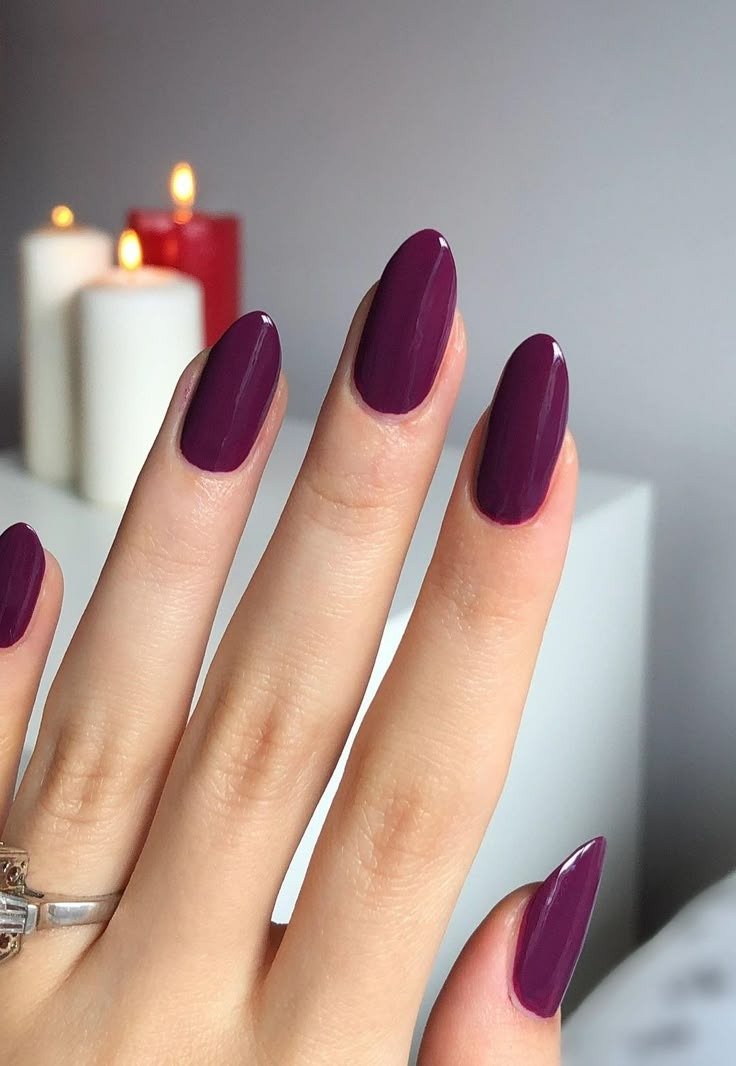Unhas coloridas da moda em tom vinho brilhante com formato amendoado, destacando elegância e sofisticação em ambiente com