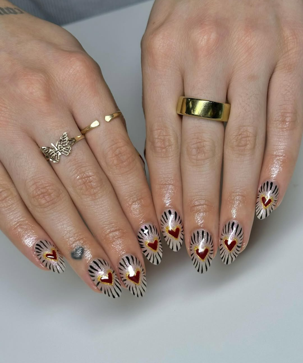 Unhas para o Carnaval com formato amendoado, fundo nude cintilante, corações vermelhos contornados de dourado.