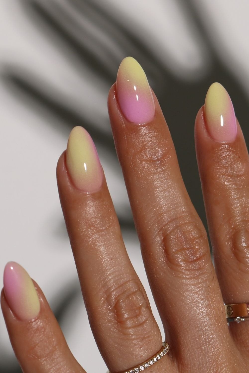 Unhas de verão com degradê em rosa e amarelo pastel, formato amêndoa e acabamento brilhante, evocando leveza e frescor.