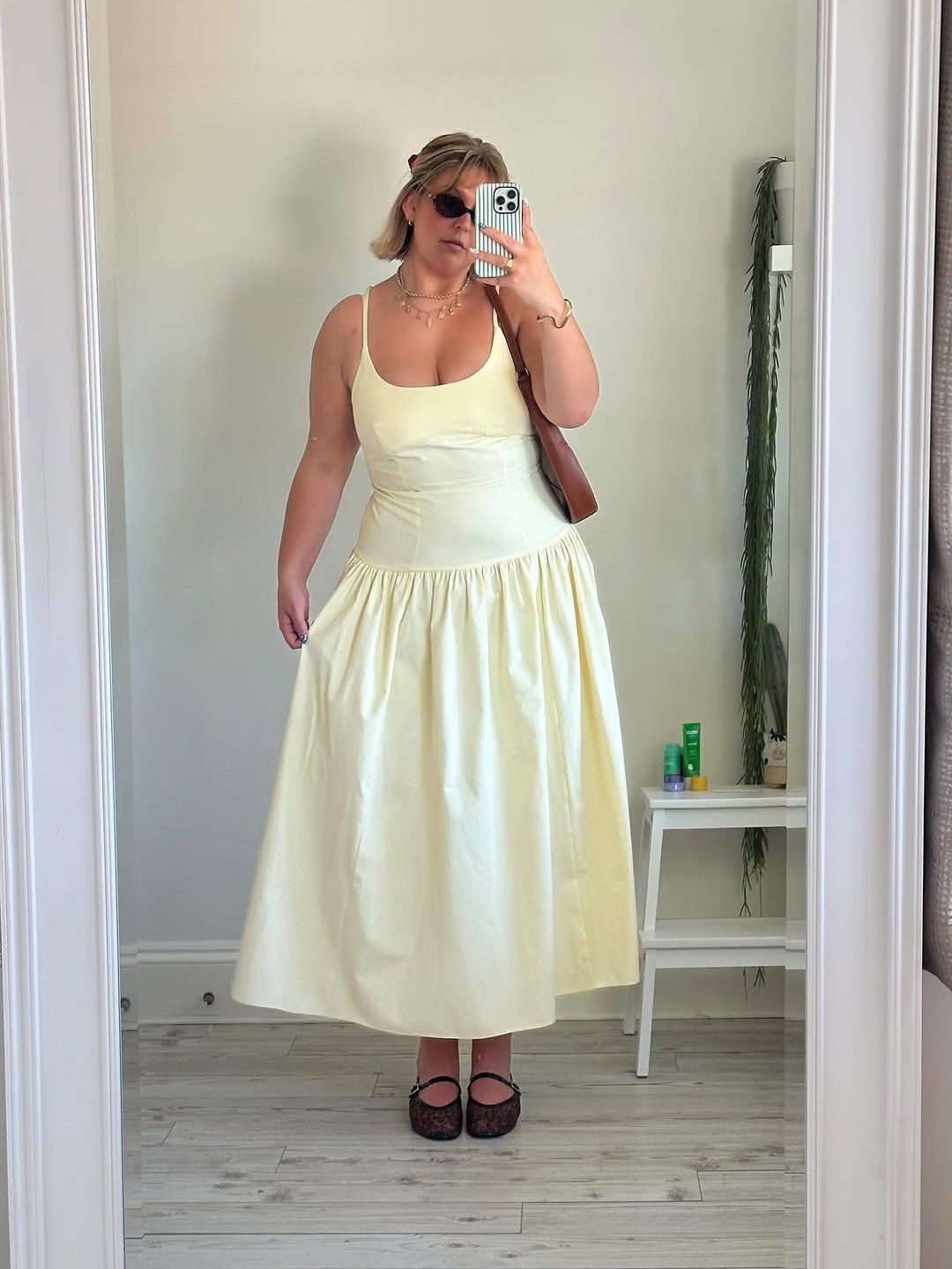 Modelo posa em vestido em crepe amarelo claro, com decote quadrado, saia rodada e alças finas, em ambiente minimalista e luz