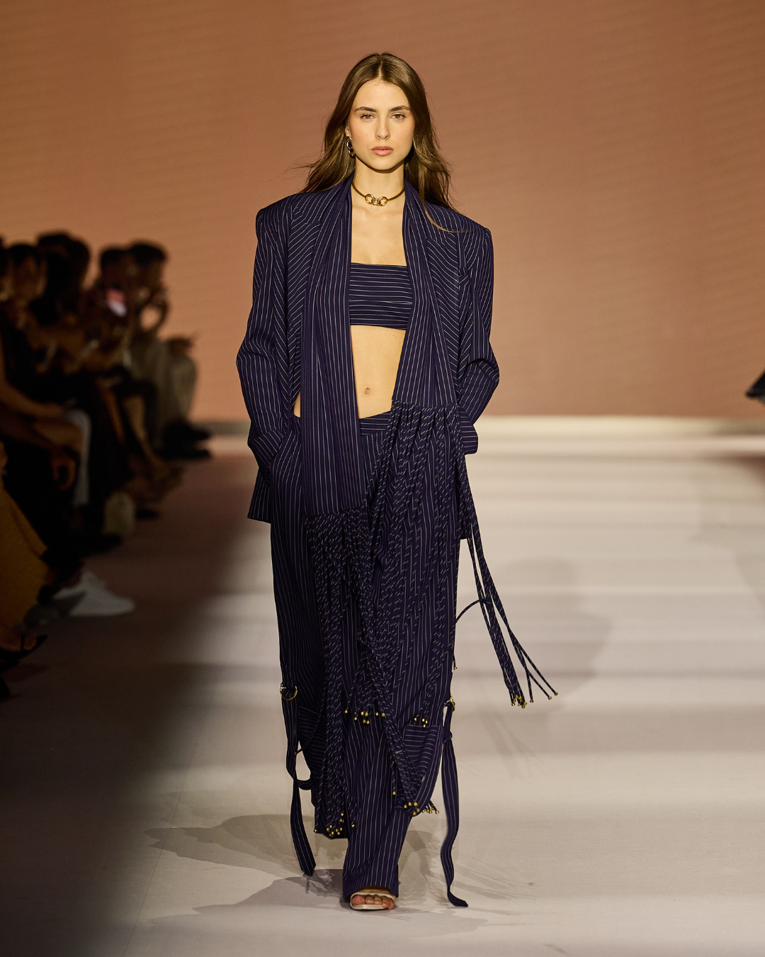 Tendências da primavera 2027: modelo desfila alfaiataria risca de giz azul-marinho com top faixa e franjas, clima
