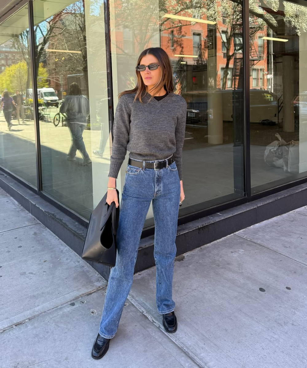 Looks com jeans para usar no trabalho: modelo posa com suéter cinza, jeans reto azul e mocassim preto.