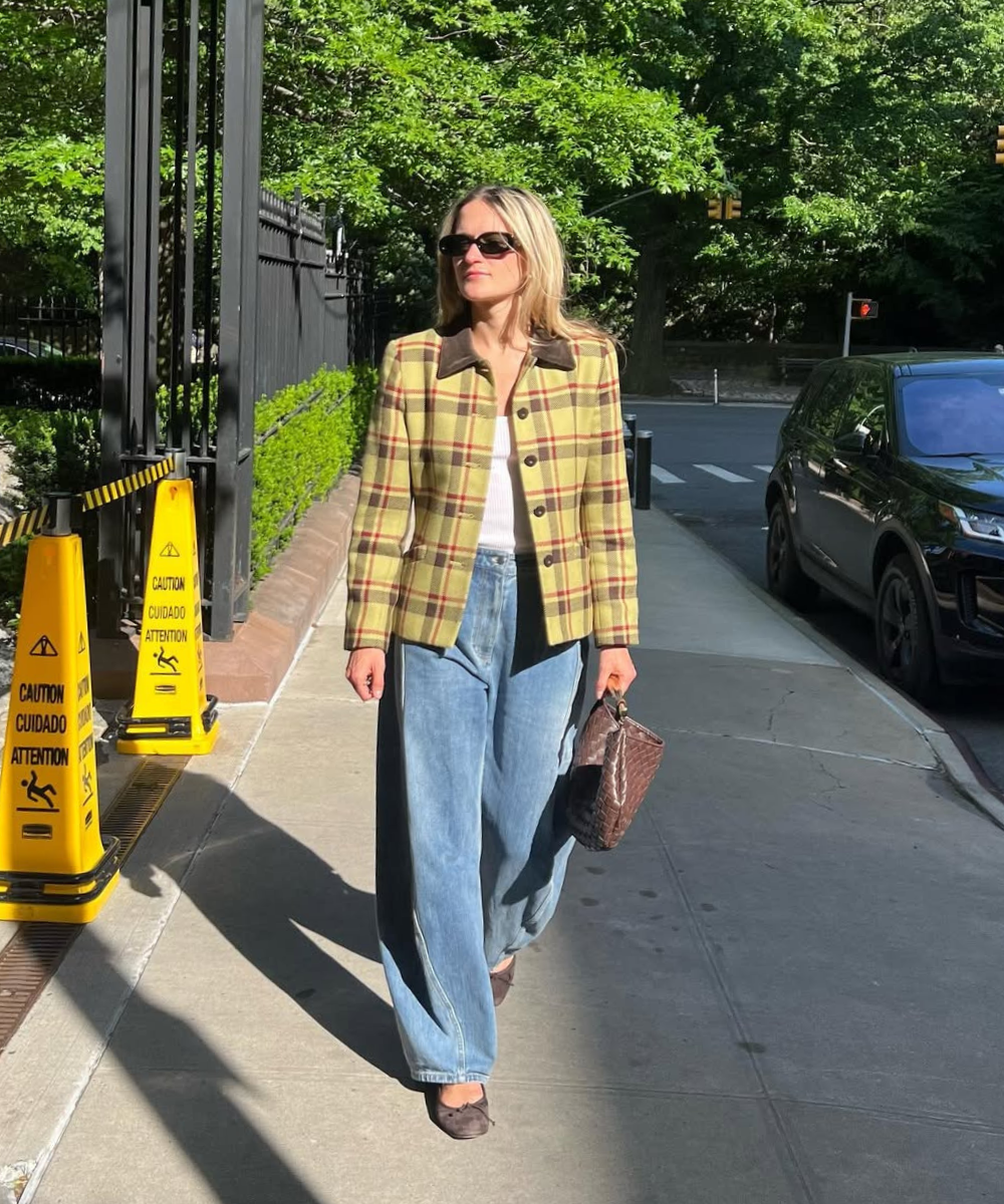 Looks com jeans para usar no trabalho: modelo caminha jaqueta amarela, jeans azul e sapatilha. 