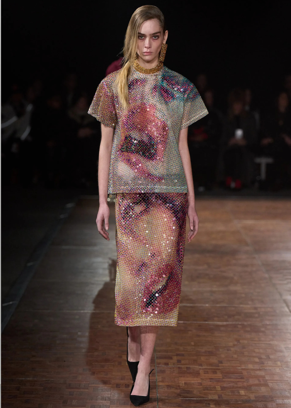 Outono/Inverno 2026: modelo desfila com conjunto midi de paetês multicoloridos, brilho intenso e elegância dramática.