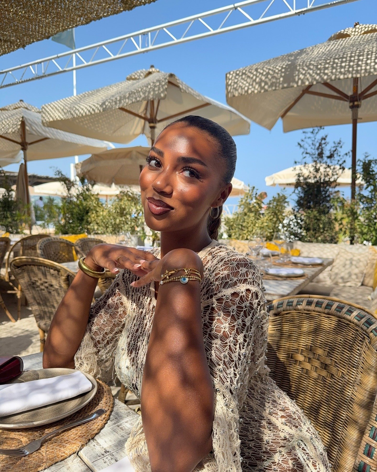 Modelo posa com blusa de crochê bege delicado, joias douradas. Representa astrologia feminina