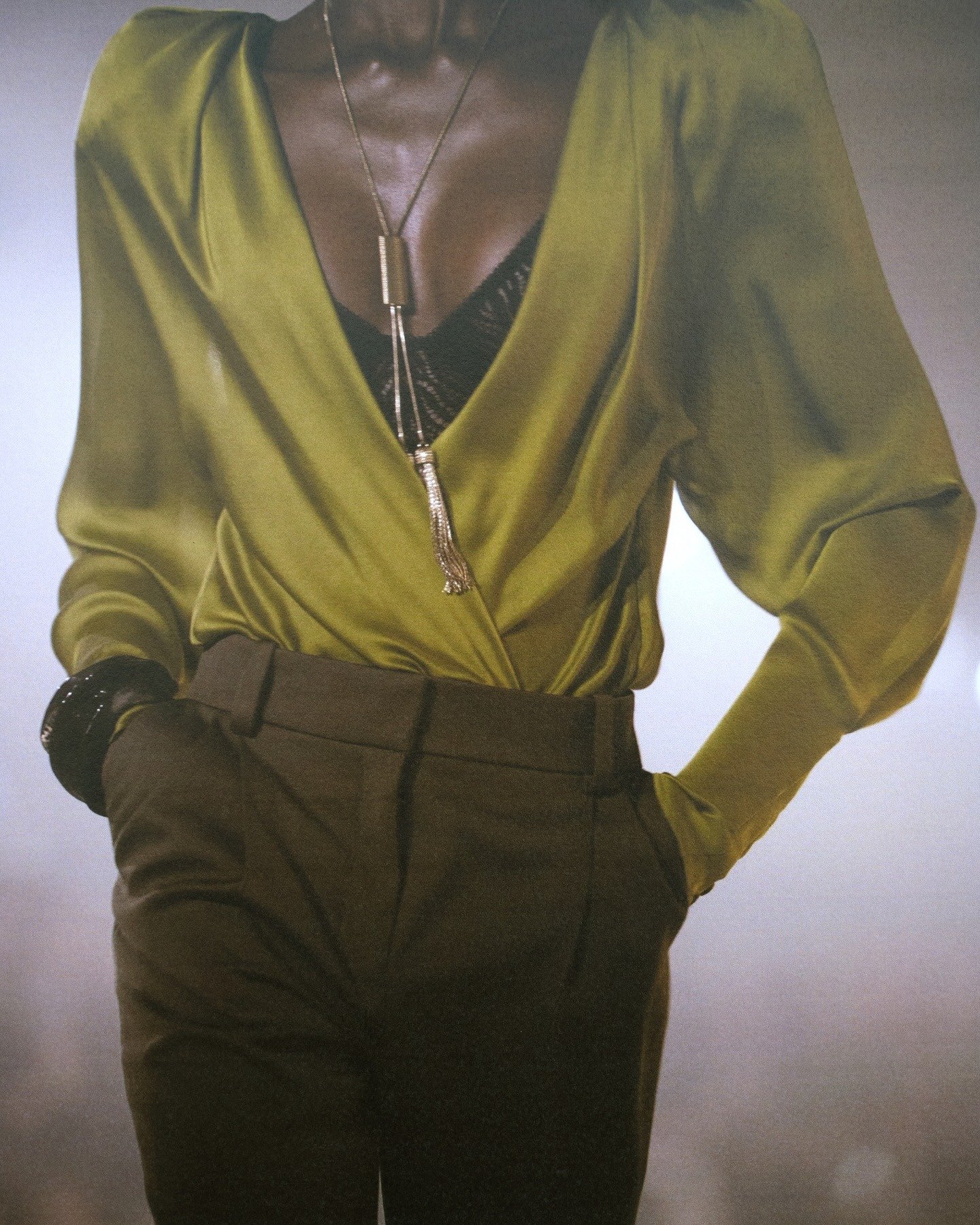 Antonin Tron destaca blusa verde oliva de tecido fluido com decote profundo, combinada a calça marrom de modelagem reta