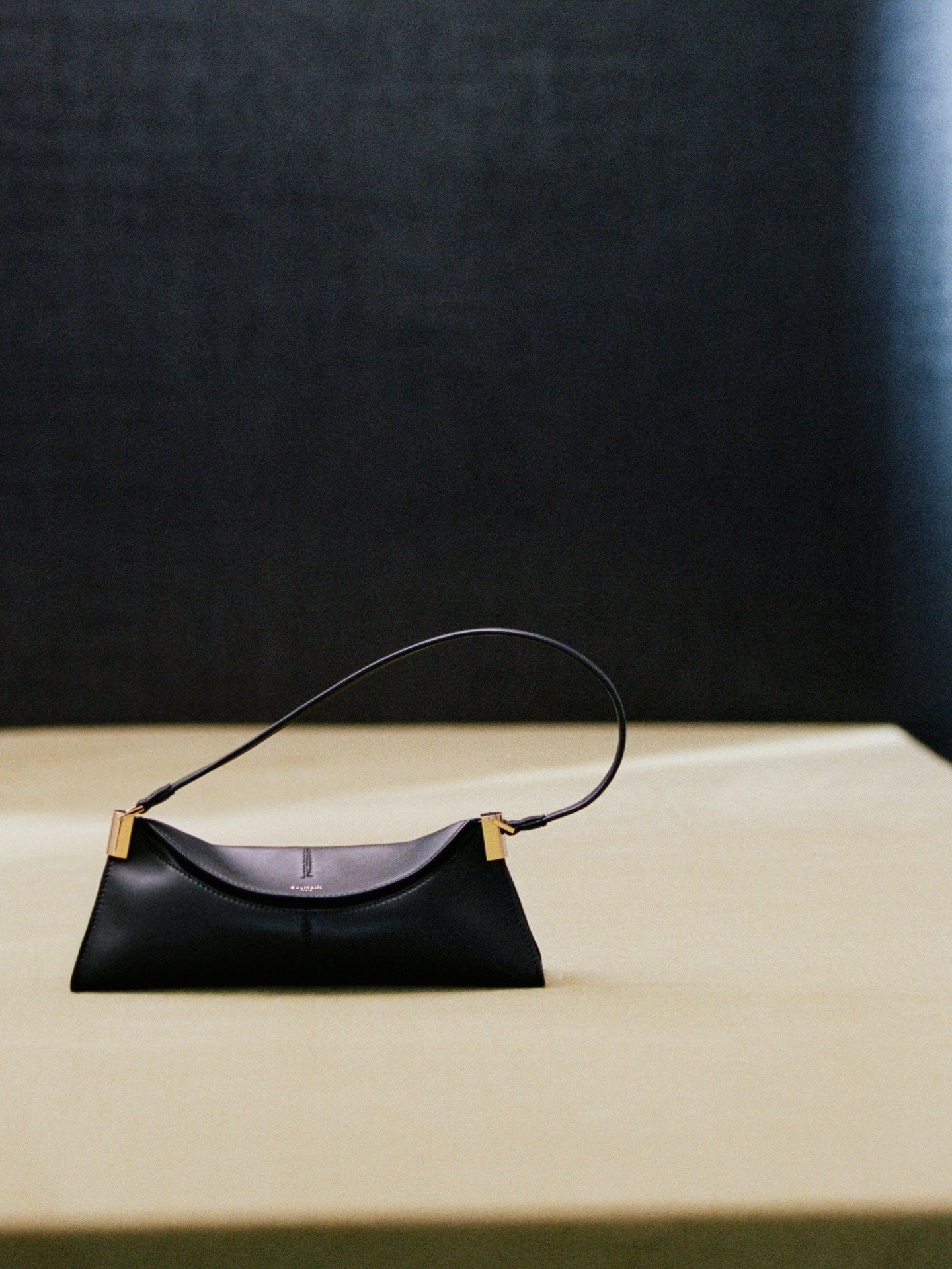 Bolsa Antonin Tron para Balmain em couro preto com design minimalista e alça fina, detalhes metálicos dourados