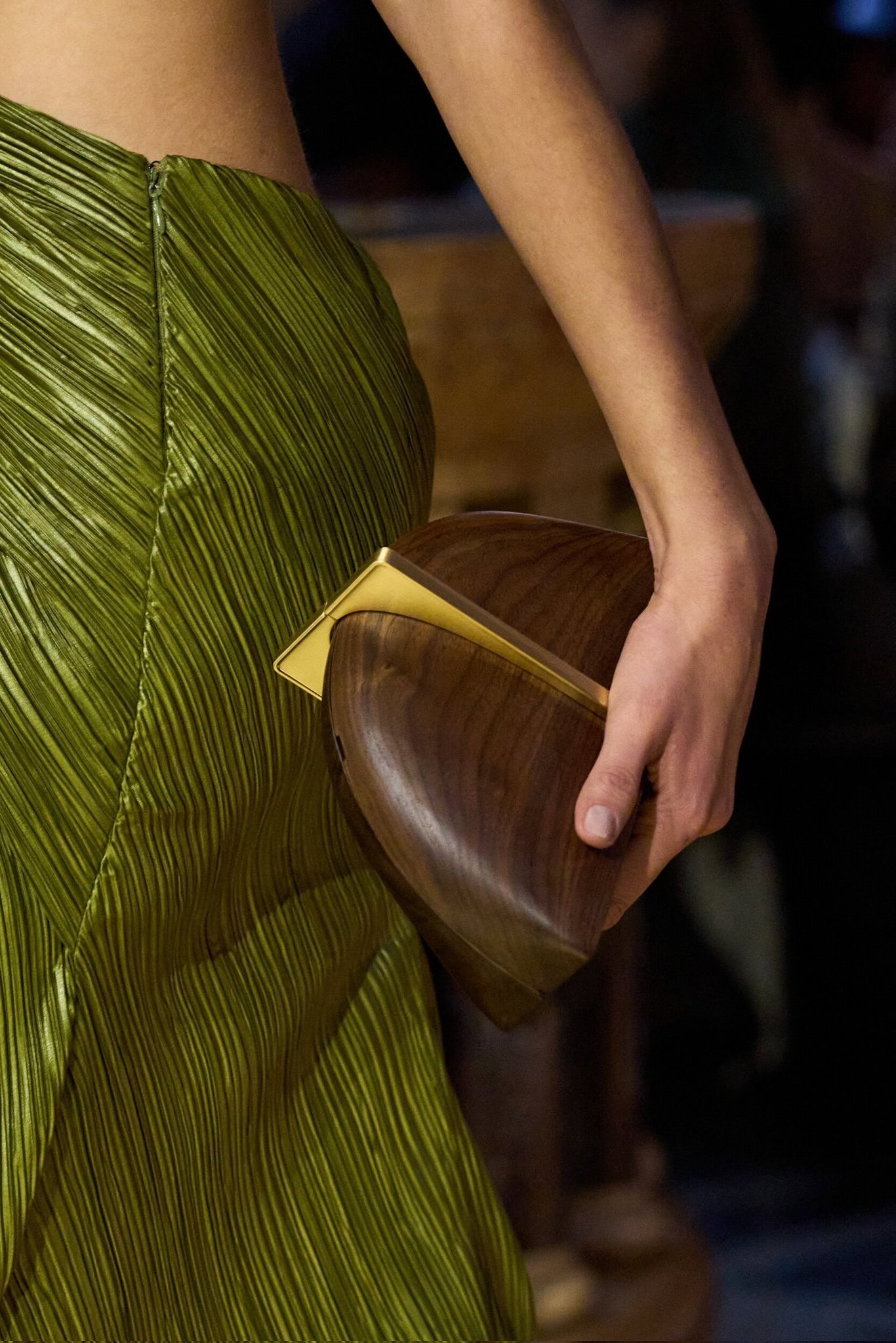 Saia verde musgo em tecido acetinado com clutch de madeira e metal dourado, elegância sofisticada para temporada de inverno