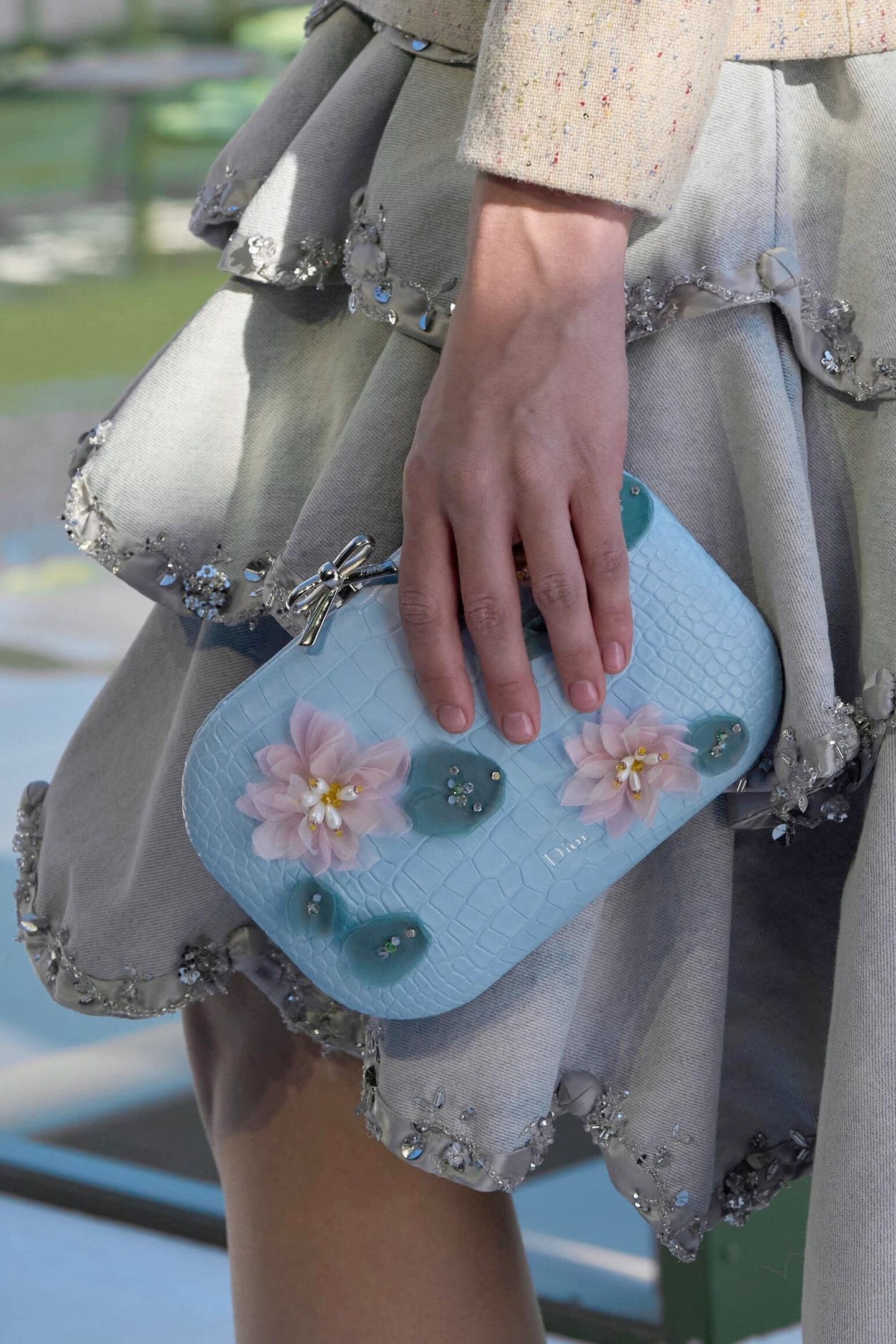 Saia em tecido cinza com bordados brilhantes e bolsa azul clara texturizada com flores delicadas para temporada de inverno