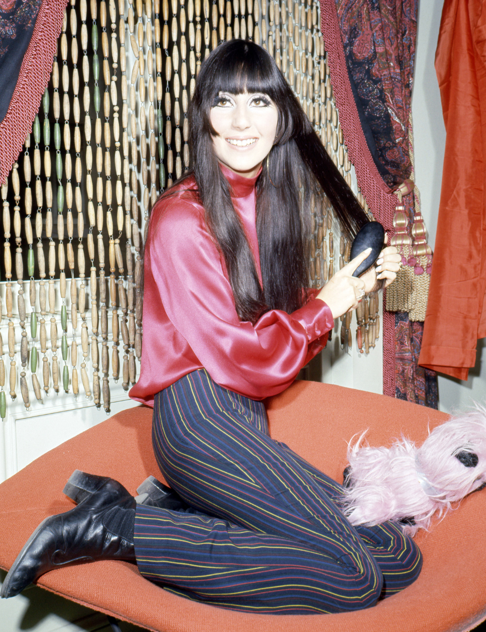 Famosa com cabelos mais icônicos longos e lisos, posando sorridente enquanto escova os fios.