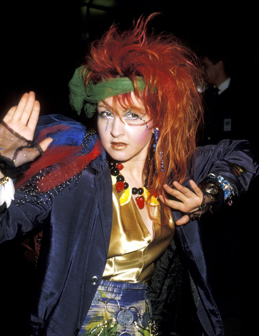 Cabelos mais icônicos das famosas com volume ruivo vibrante, faixa verde, maquiagem artística e look colorido e ousado.