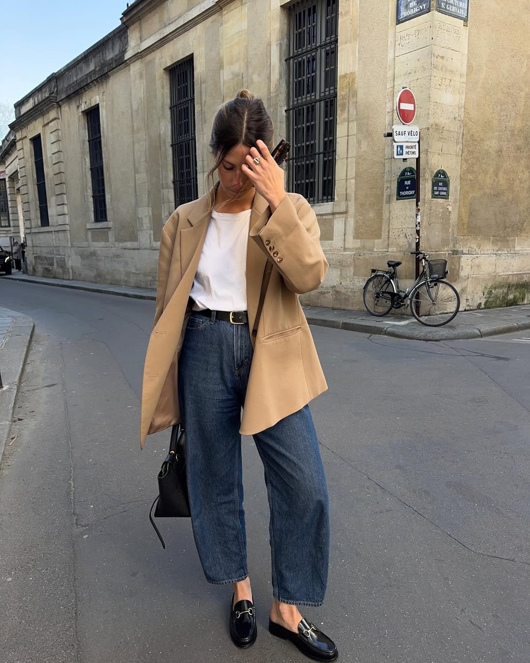 Mocassim feminino com calça jeans reta, blazer bege e camiseta branca em look urbano elegante; modelo posa.