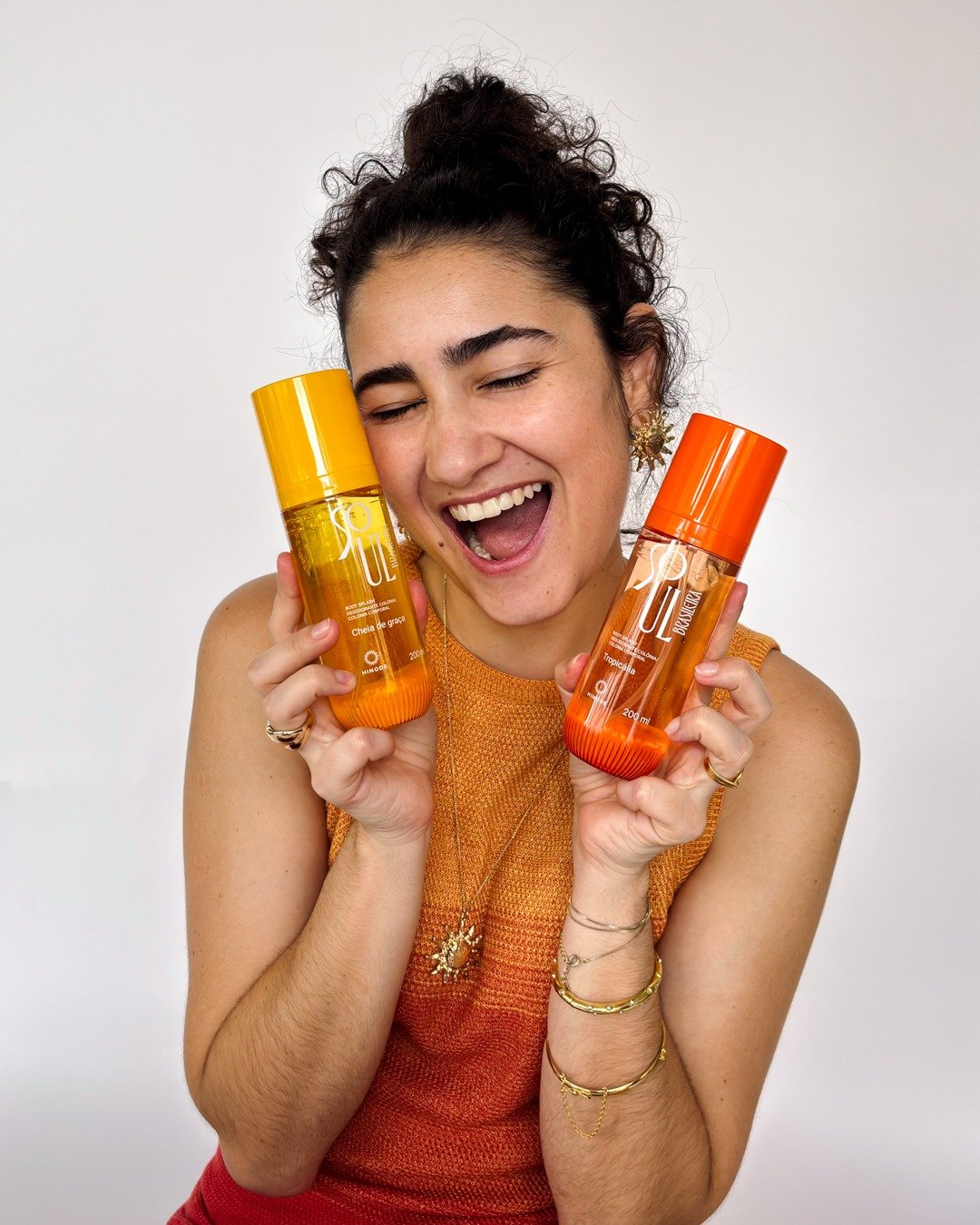 Modelo sorridente segura colônias em frascos laranja e amarelo de como ficar mais cheirosa e hidratada