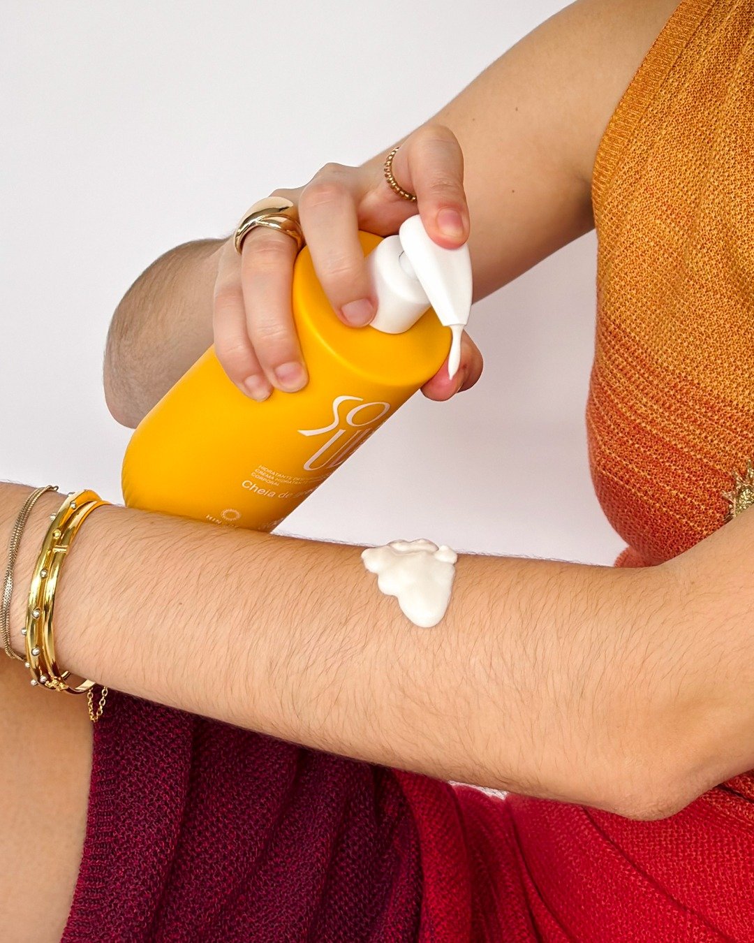 Mulher aplica creme hidratante amarelo em braço, como ficar mais cheirosa e hidratada com produtos da hinode