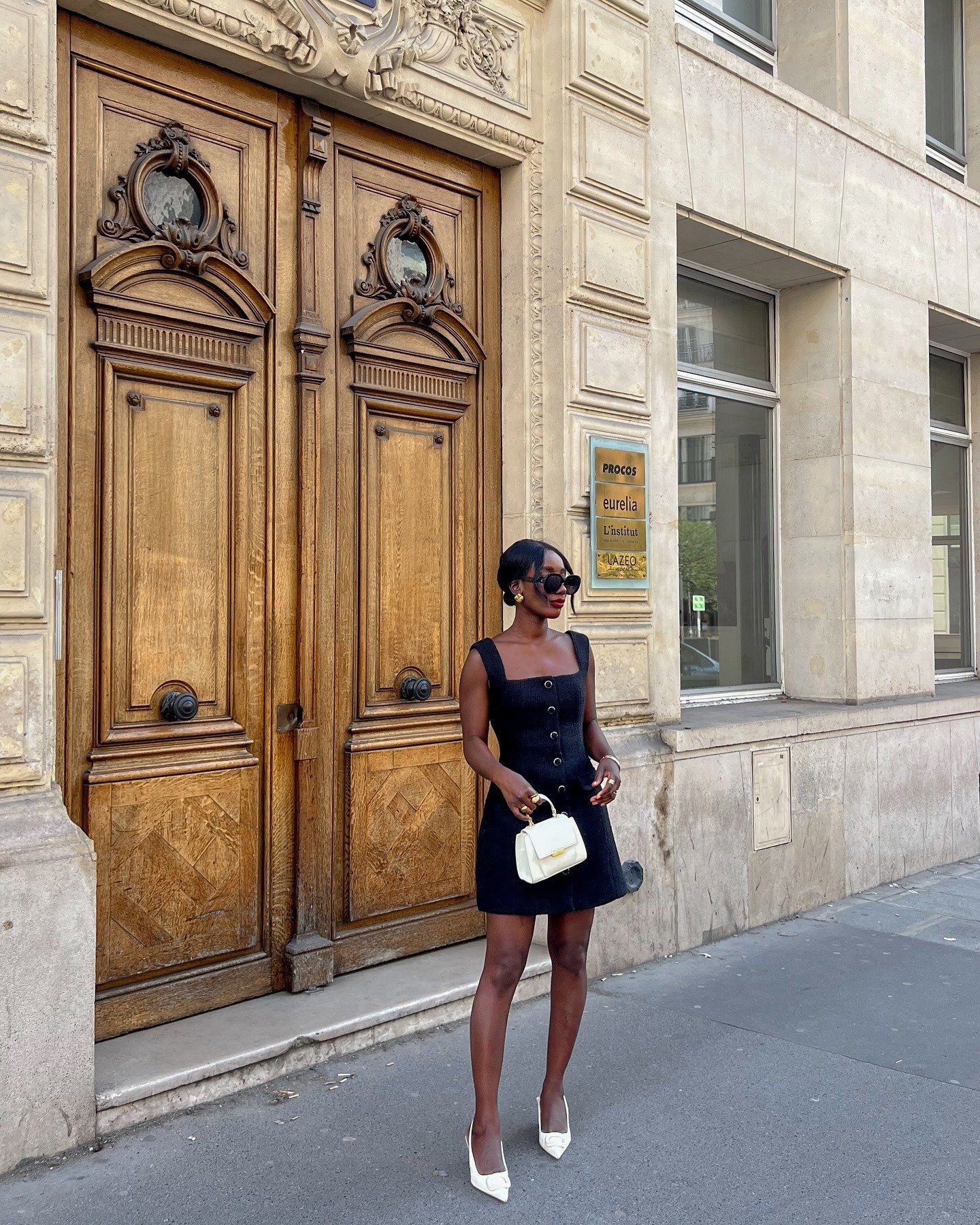 Modelo posa de vestido preto estruturado e scarpin branco, entre cores de sapato que combinam com tudo, em clima elegante.