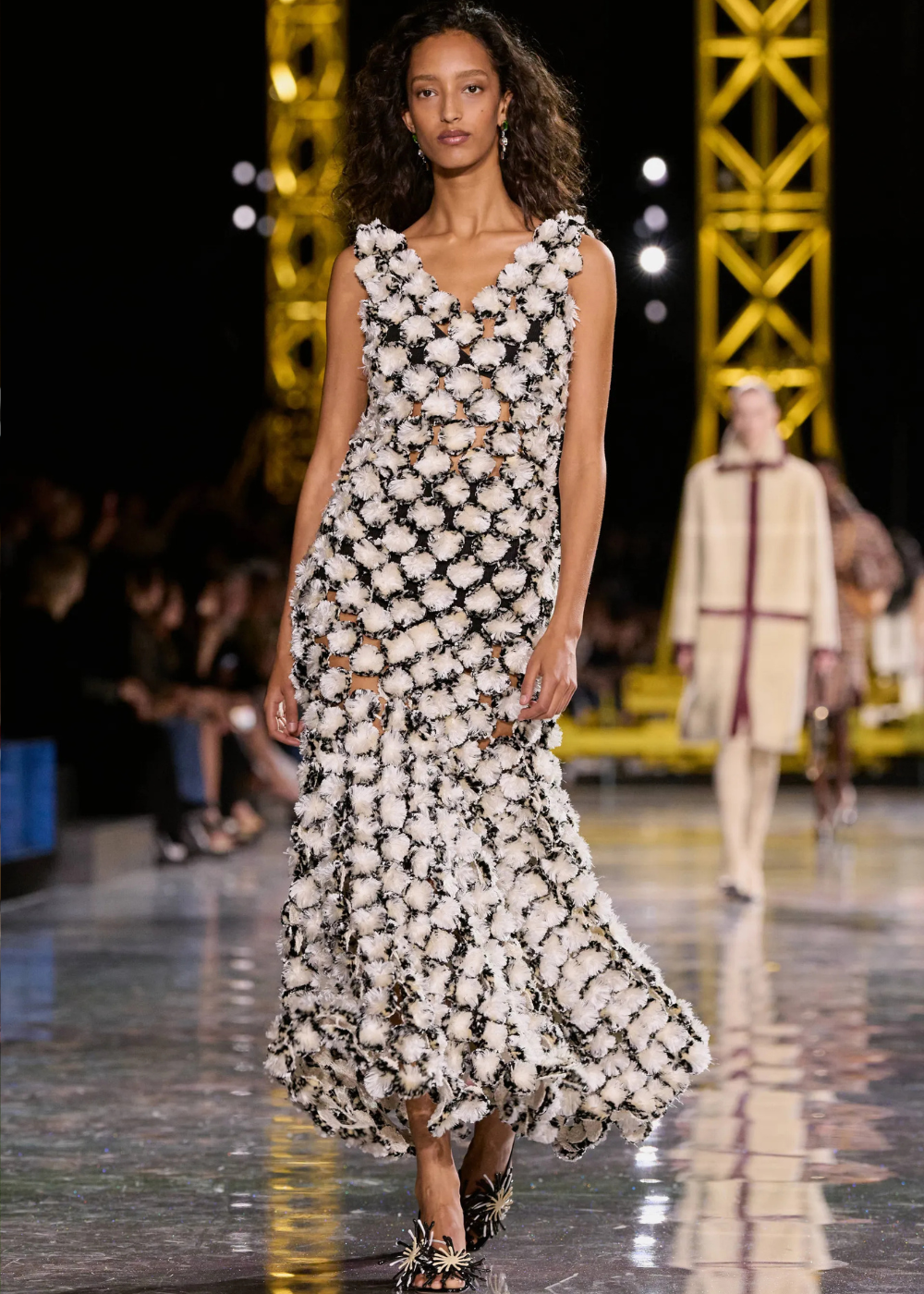 Outono/Inverno 2026: modelo desfila em vestido longo floral texturizado preto e branco, com elegância dramática na passarela.