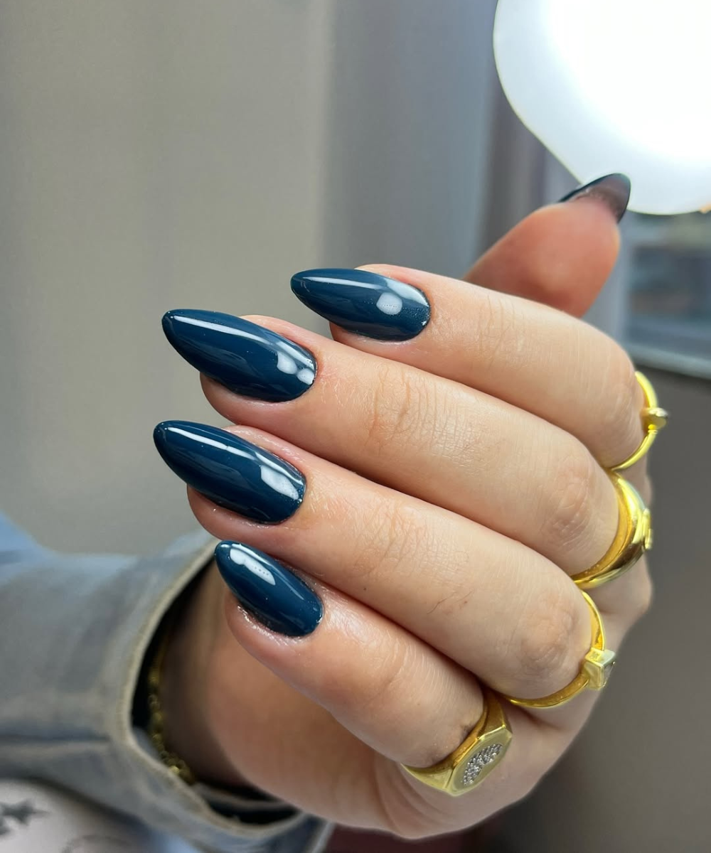 Esmaltes para o outono em azul-petróleo brilhante destacam unhas amendoadas, anéis dourados e clima sofisticado.