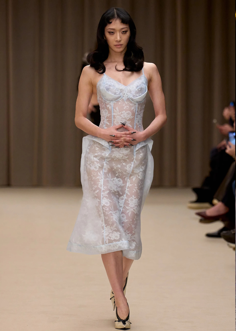 Outono/Inverno 2026: modelo desfila em vestido midi azul-claro de renda e transparência, com elegância etérea na passarela.