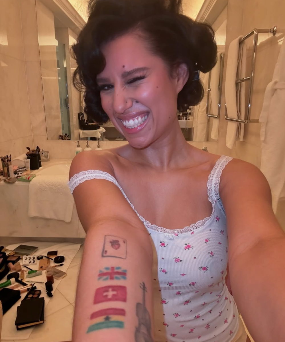 Preparação para escova modelada em cabelo preso, modelo sorri e pisca no banheiro com regata floral branca rendada.