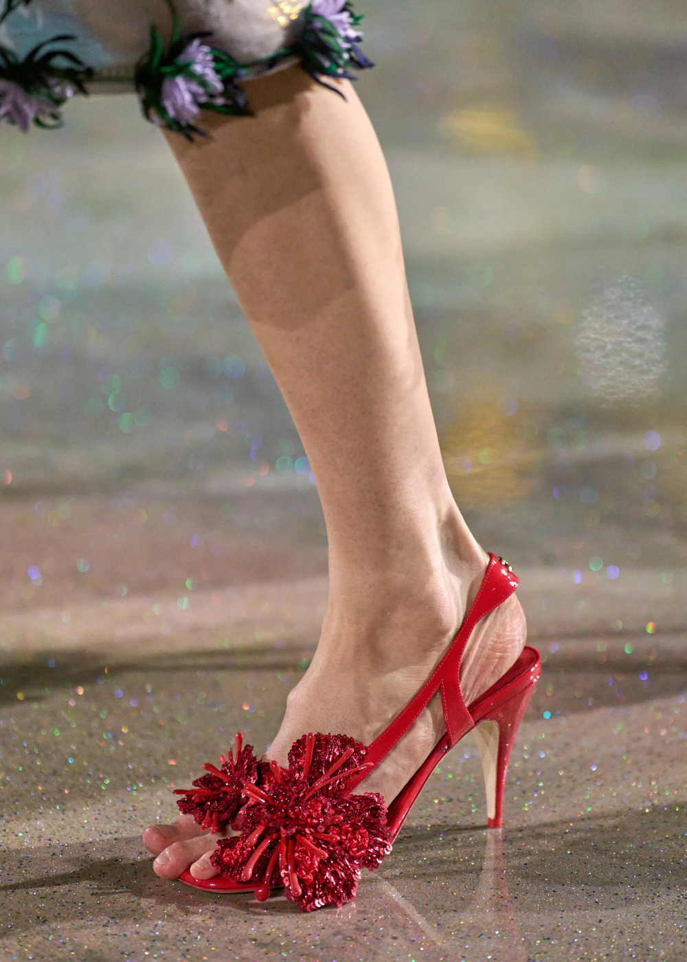 Outono/Inverno 2026 em sandália vermelha de salto fino com flor 3D brilhante, sobre piso cintilante e clima glamouroso