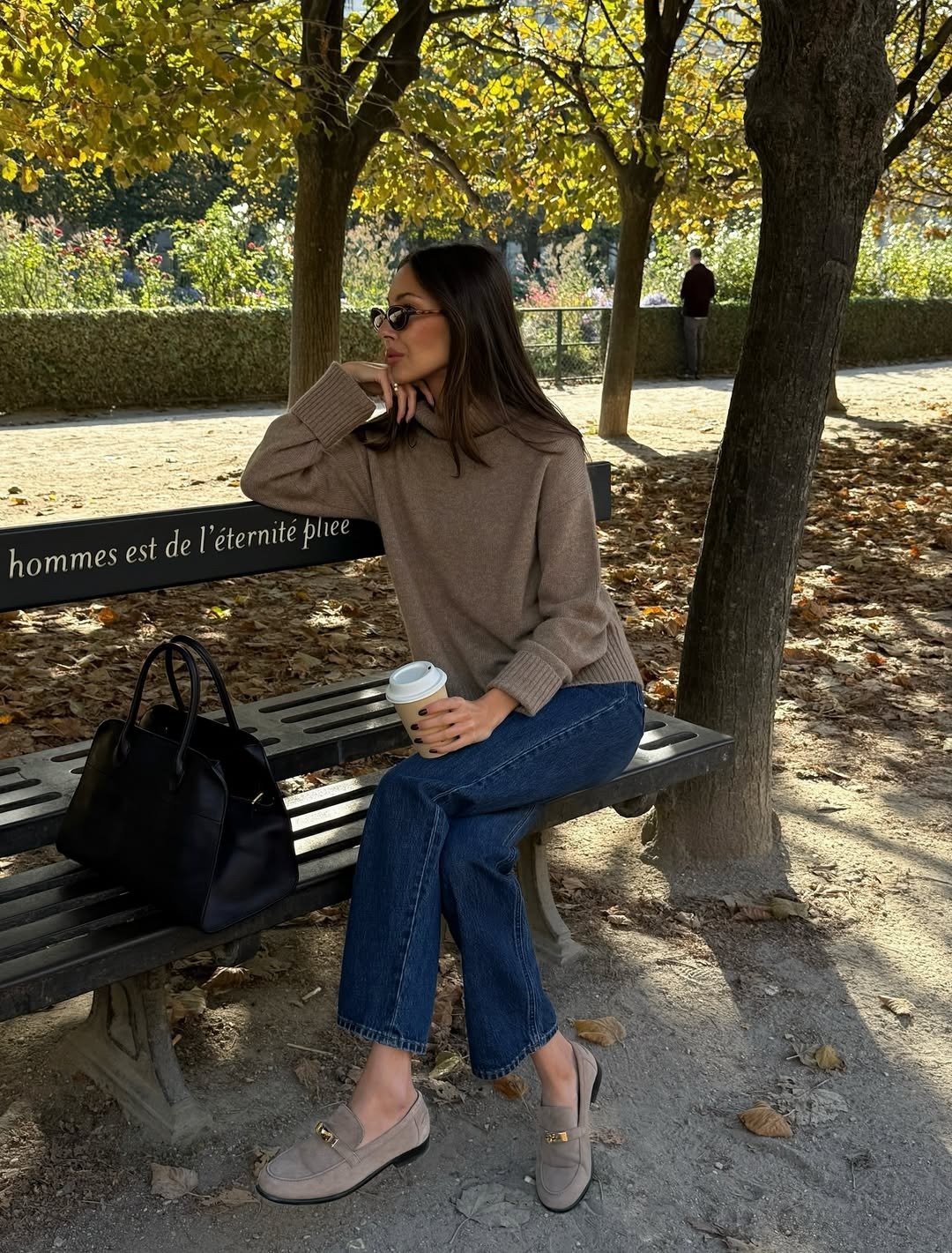 Como usar mocassim feminino com calça jeans: modelo posa sentada com tricô bege, jeans reto e mocassim