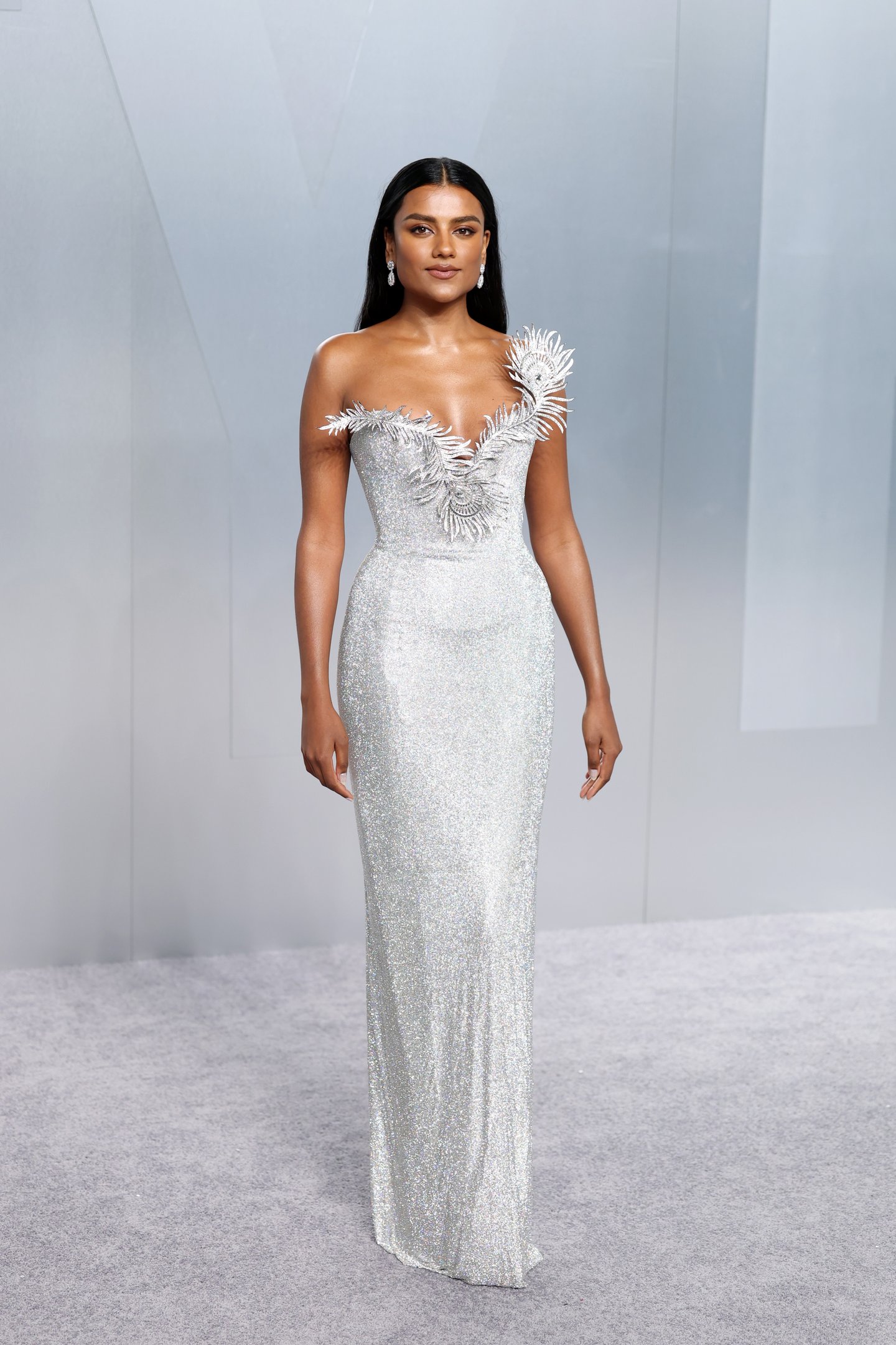 After party do Oscar 2026: modelo posa com vestido prata brilhante, silhueta coluna e bordado escultural, clima sofisticado.