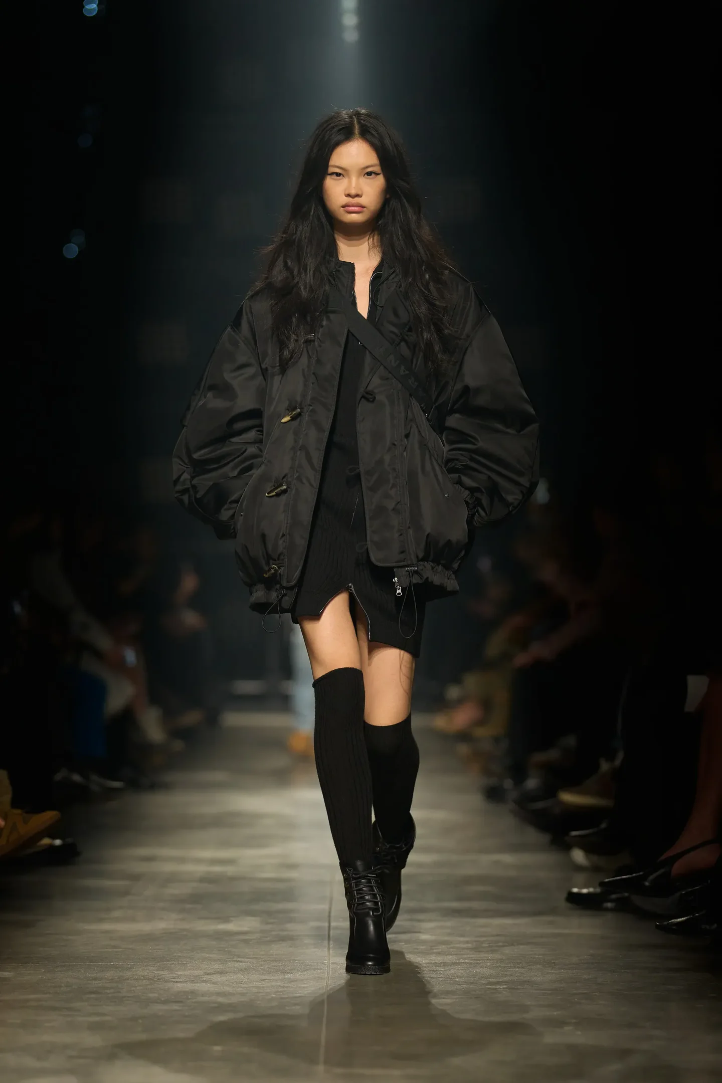Modelo Isabel Marant desfila com jaqueta oversized de nylon preta, vestido curto texturizado e botas de cano alto