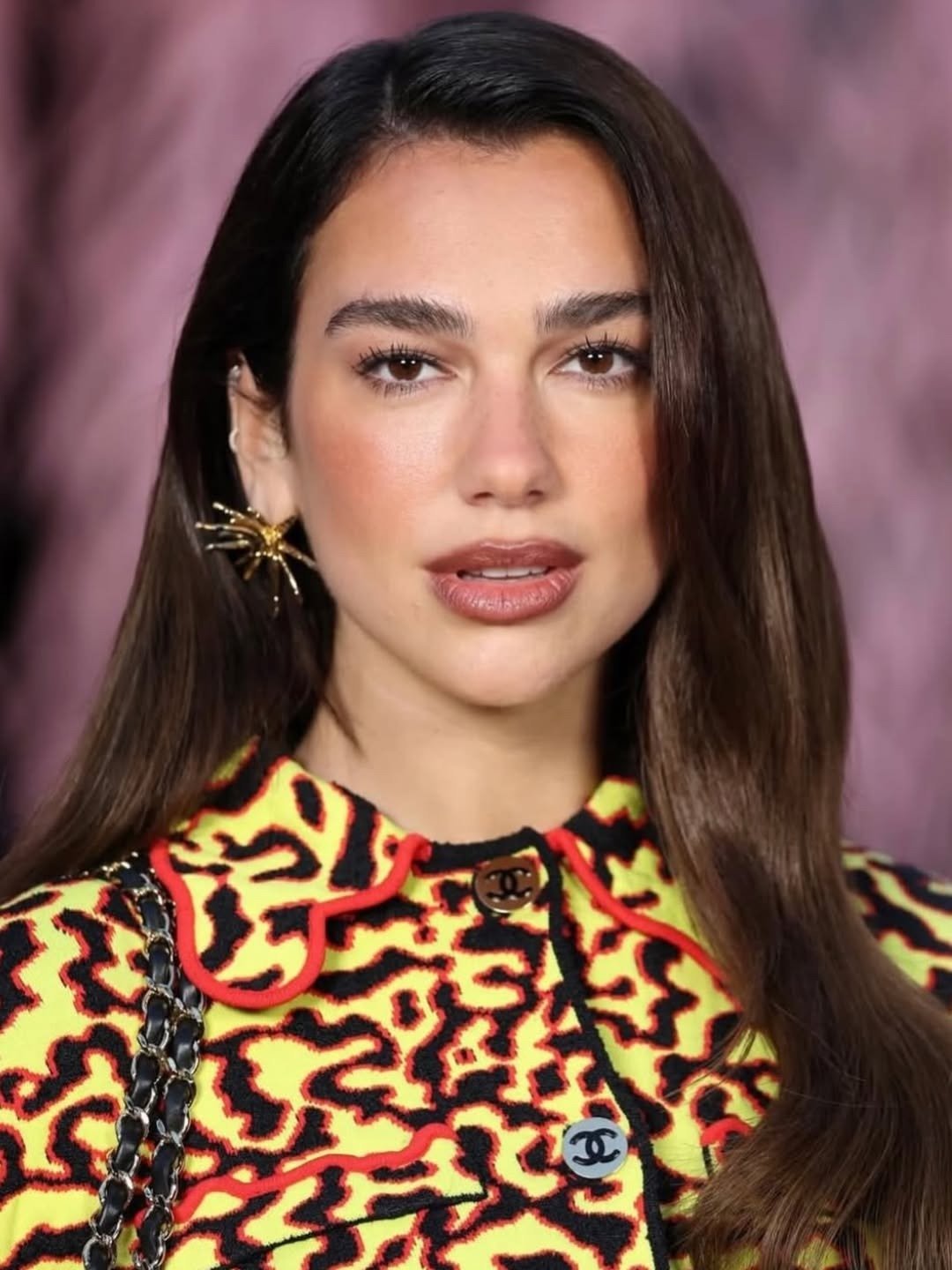 Modelo exibe halo lips em tom nude rosado com acabamento luminoso, combinando com casaco estampado amarelo e preto e brinco