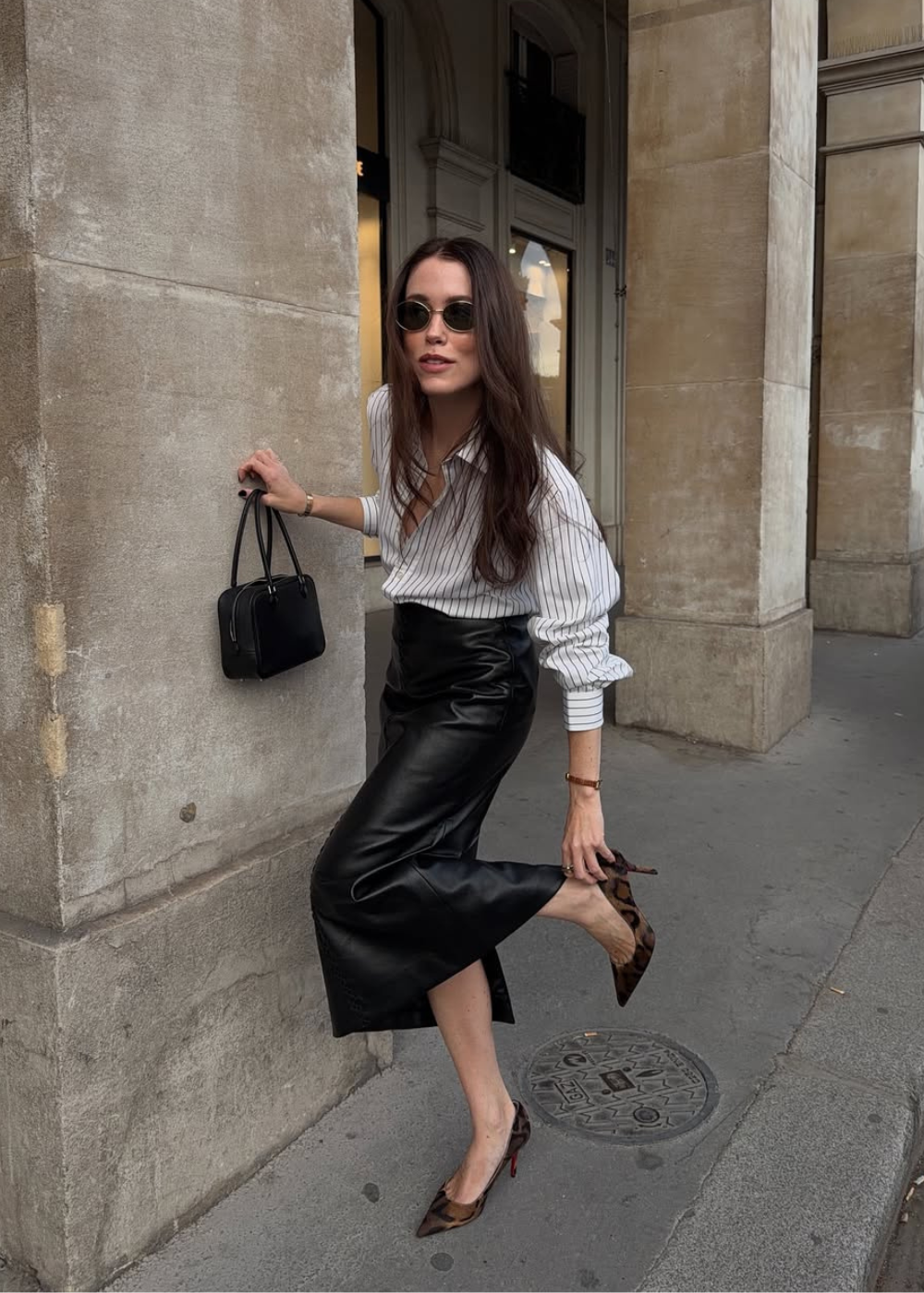 Look com saia lápis no outono em couro preto, camisa branca listrada, scarpin animal print e bolsa preta.