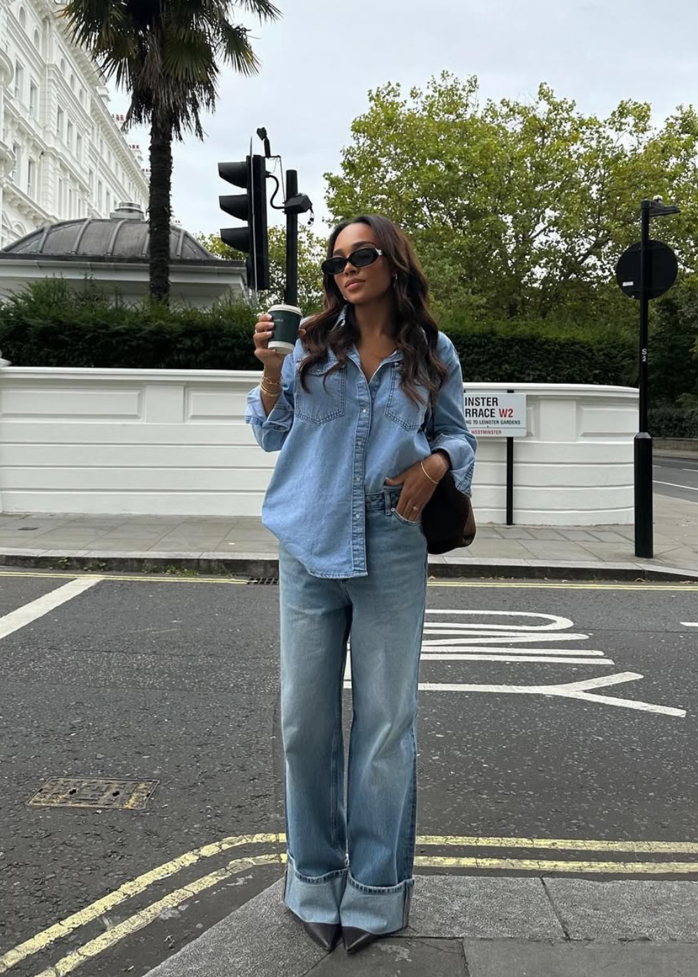 Mulher posa confiante com camisa jeans oversized e calça wide leg, combinando looks estilosos e confortáveis em tons azul.