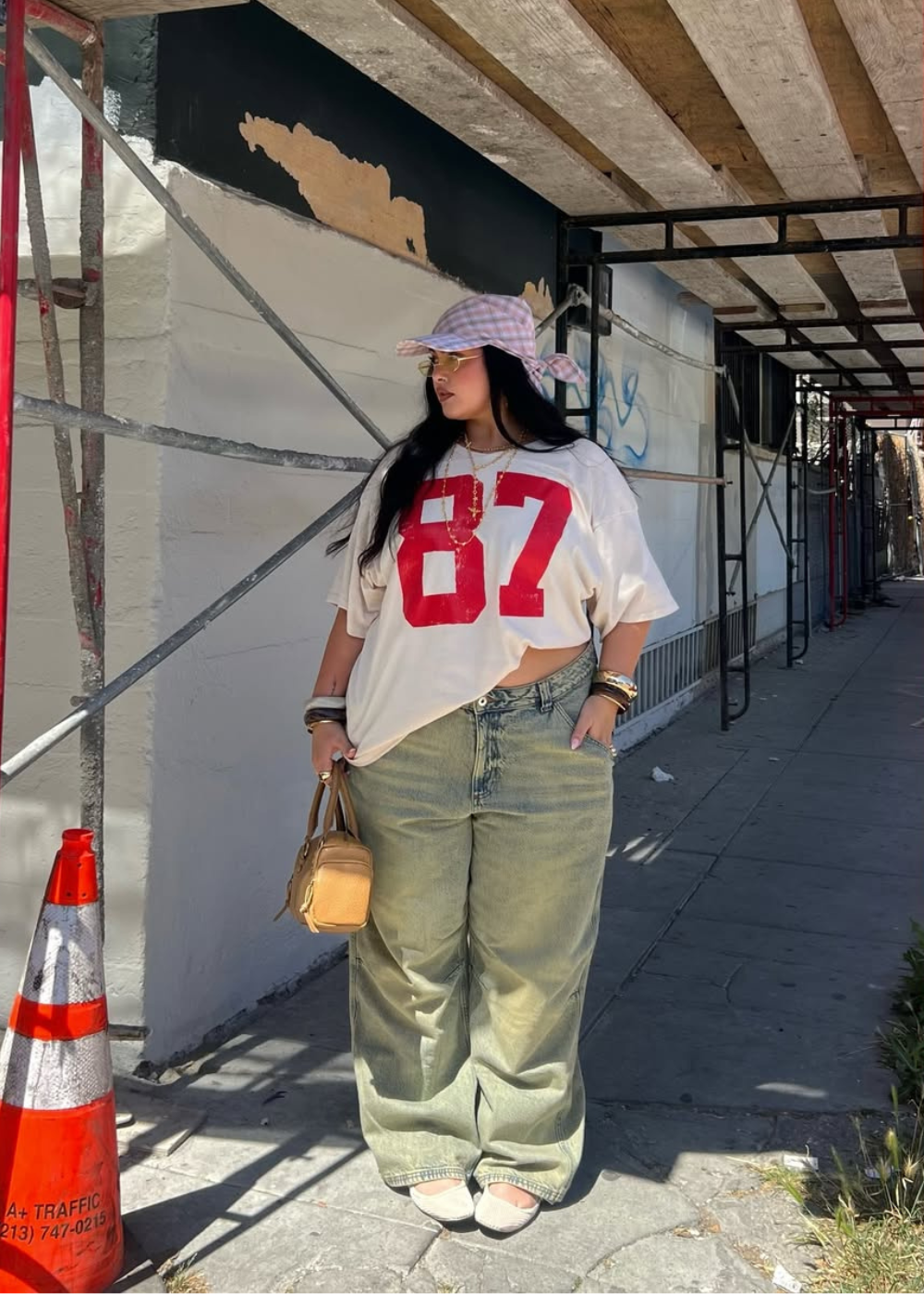 Looks para o Lollapalooza 2026 com camiseta oversized branca estampada em vermelho, calça jeans larga verde, chapéu xadrez.