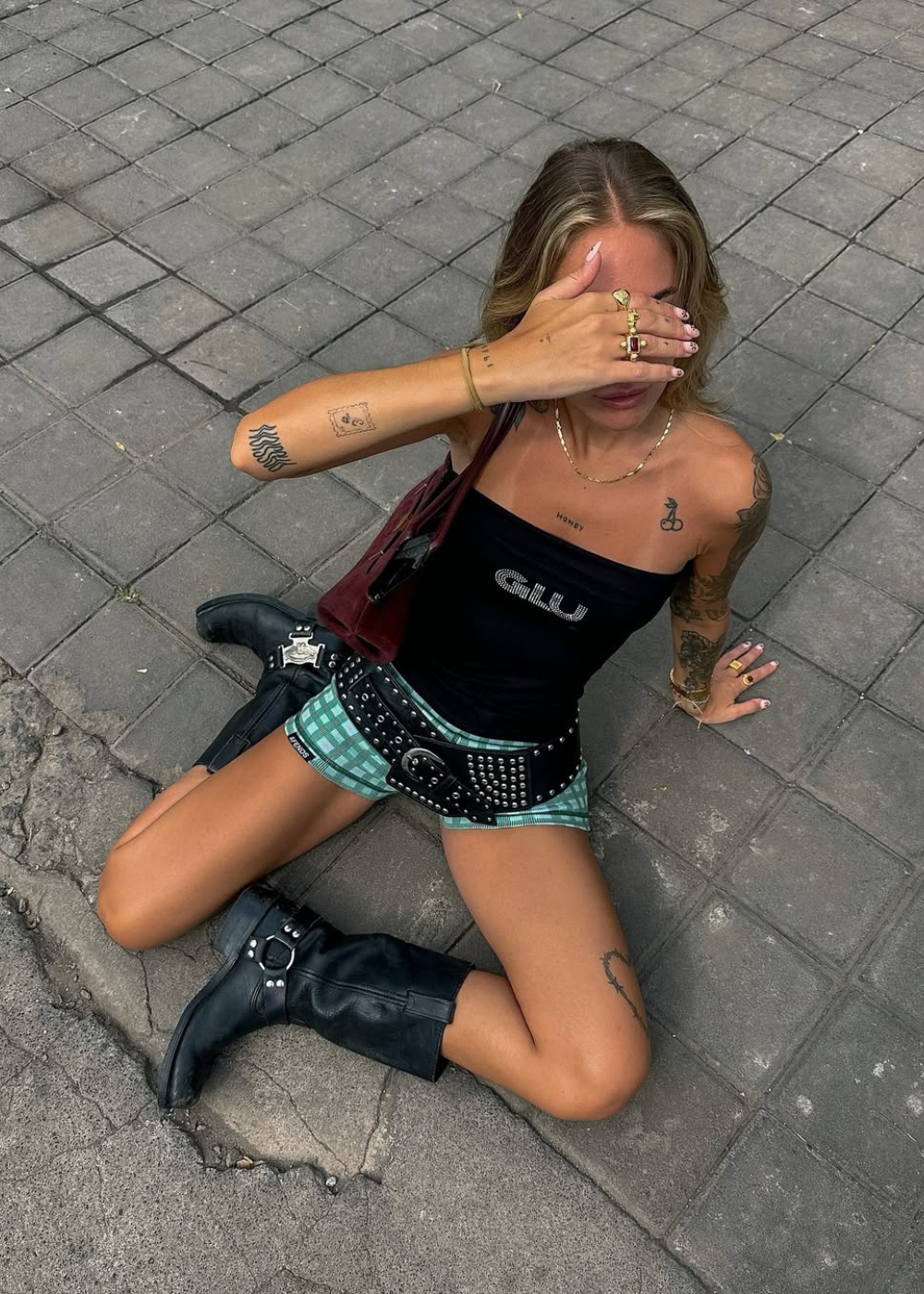 Looks para o Lollapalooza 2026 com top preto justo, shorts xadrez verde, botas de couro pretas e acessórios punk.