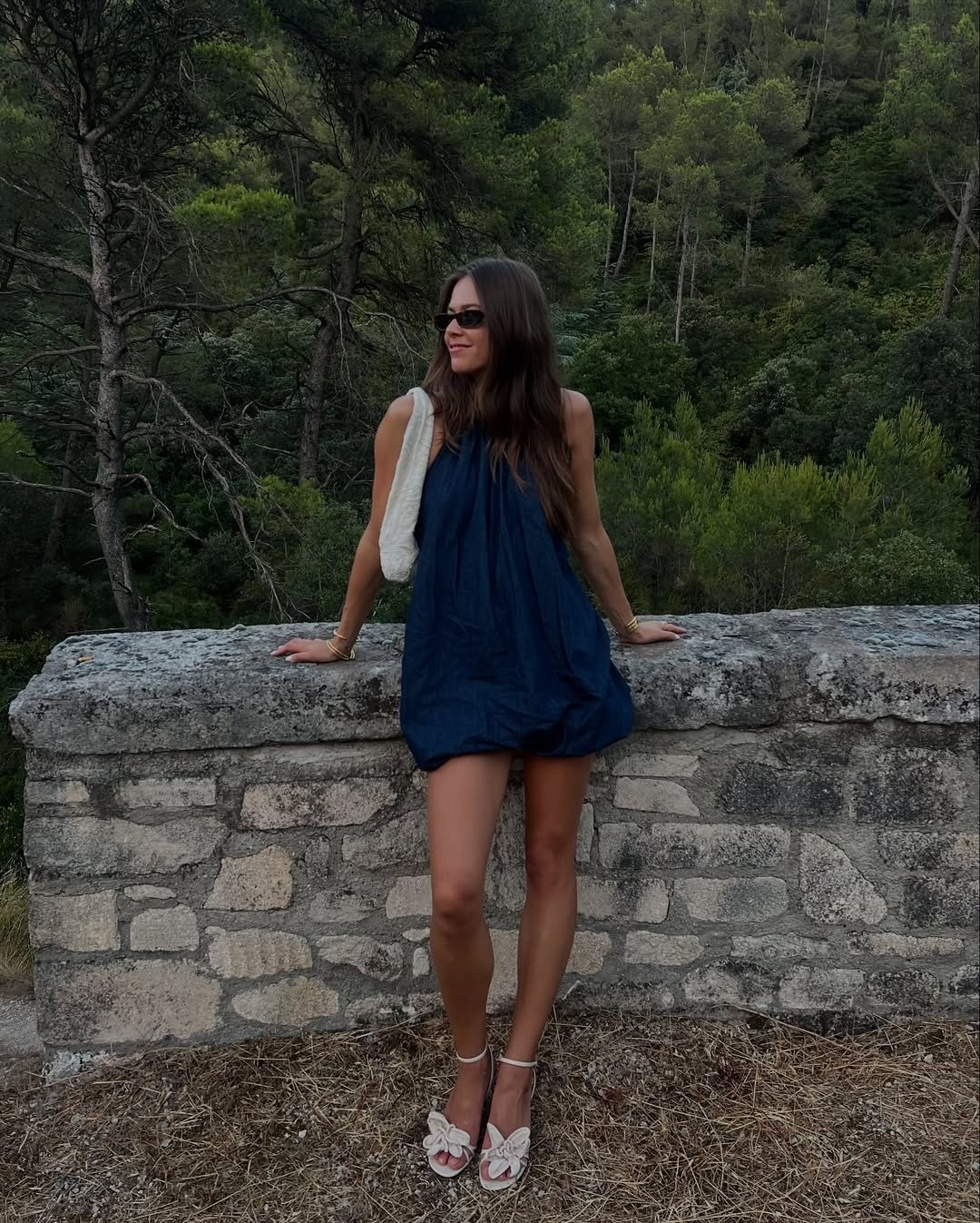 Modelo posa com vestido tendência 2026 azul marinho de modelagem ampla e curta, tecido leve, combinando sandálias brancas e