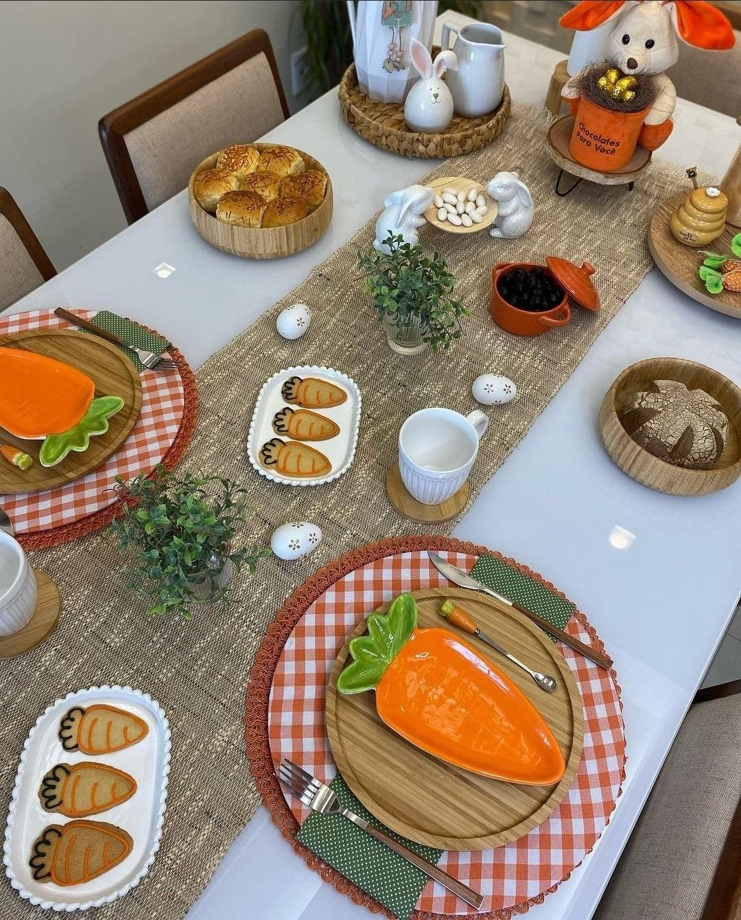 Mesa posta para Páscoa com louça de cenoura, madeira, xadrez laranja e juta, em clima acolhedor; Texto: chocolates para você