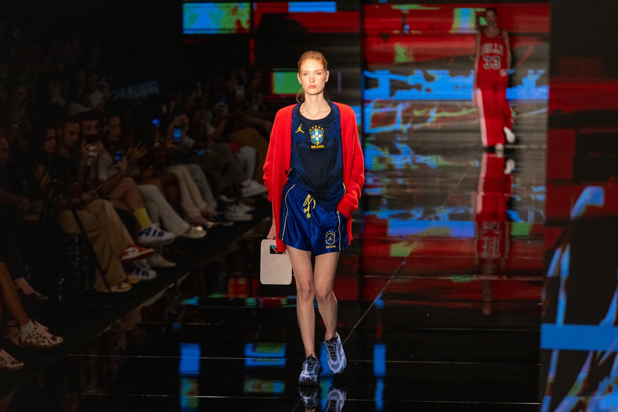 Moda inverno 2026: modelo desfila com cardigan vermelho e look esportivo azul; Texto: BRASIL CHICAGO 33