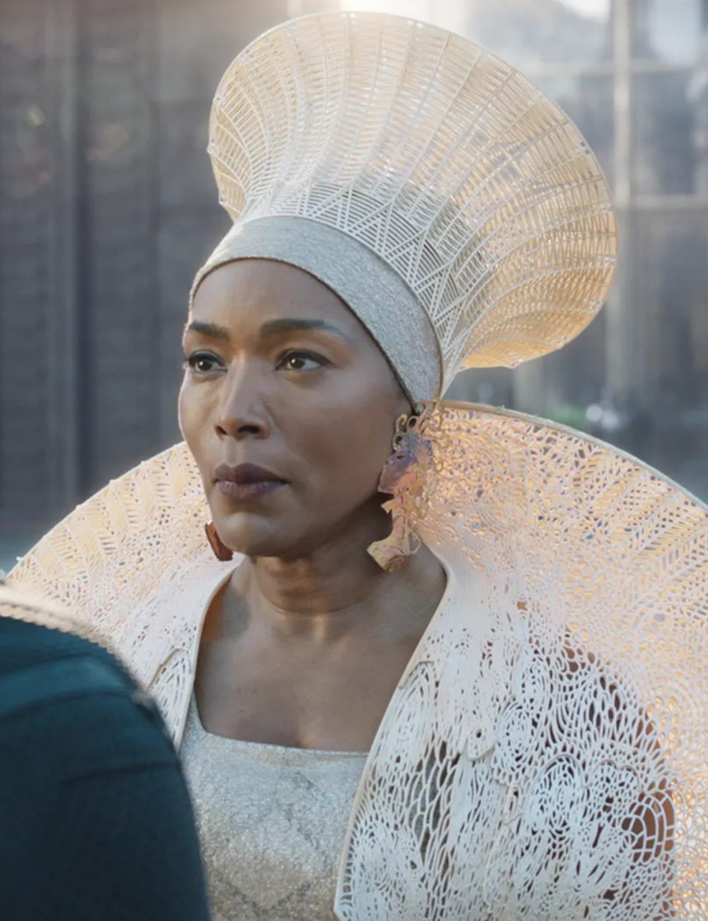 Ruth E. Carter destaca estilo com modelagem estruturada em tecido prateado e renda branca detalhada.