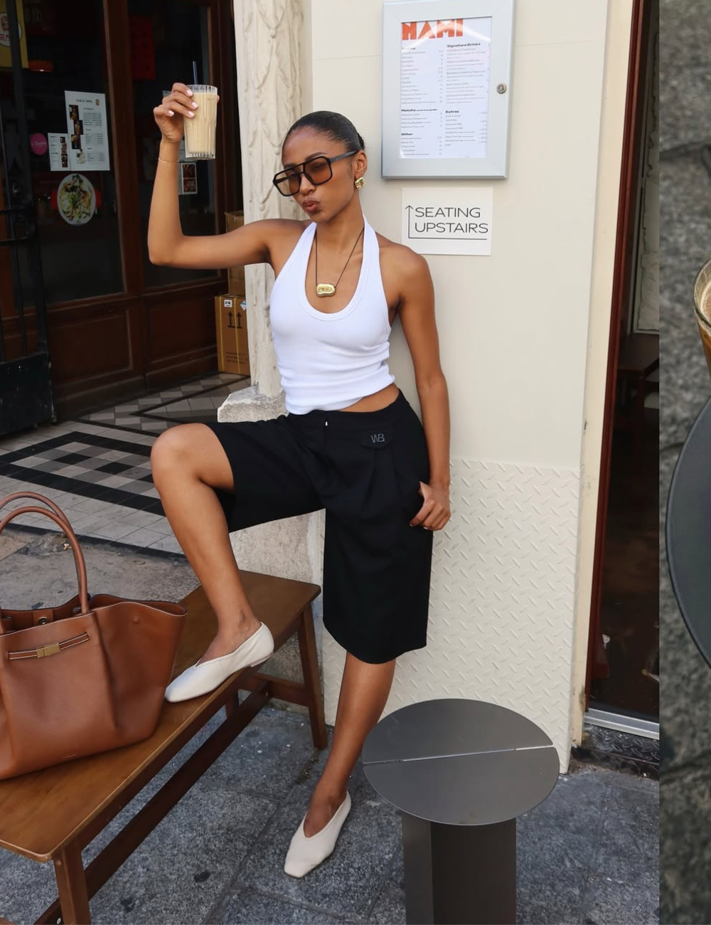 Modelo posa com sapatilha amendoada off-white, regata branca e bermuda preta em clima urbano elegante.