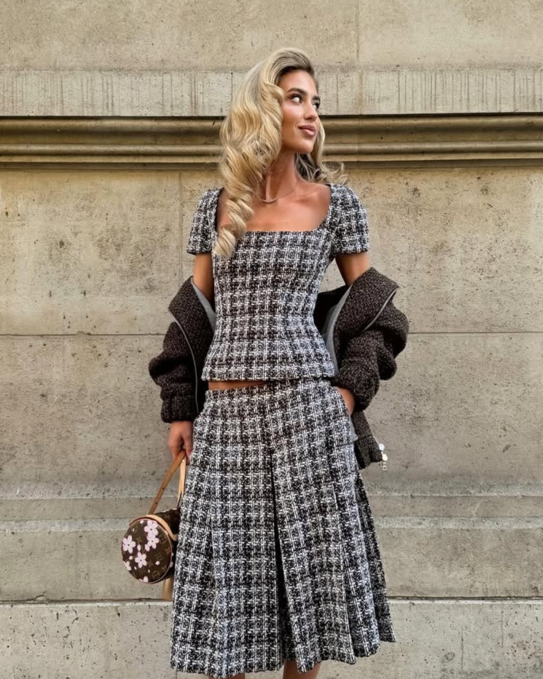 Modelo posa com conjunto tweed preto e branco, casaco marrom e bolsa, look para sapatos confortáveis femininos