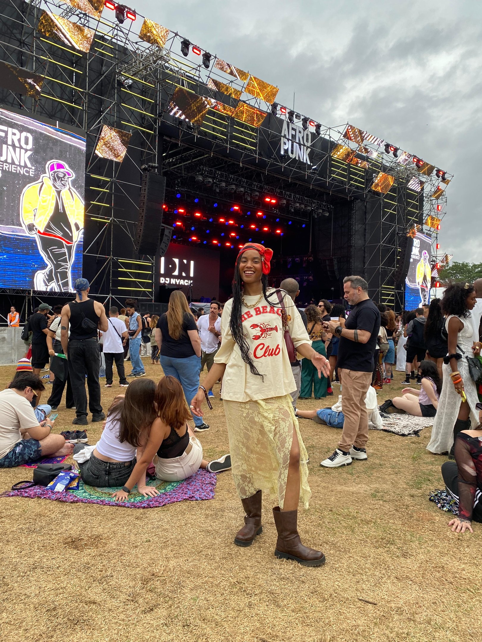 Modelo posa com melhores sapatos de couro marrom, camiseta oversized e saia rendada bege em festival.