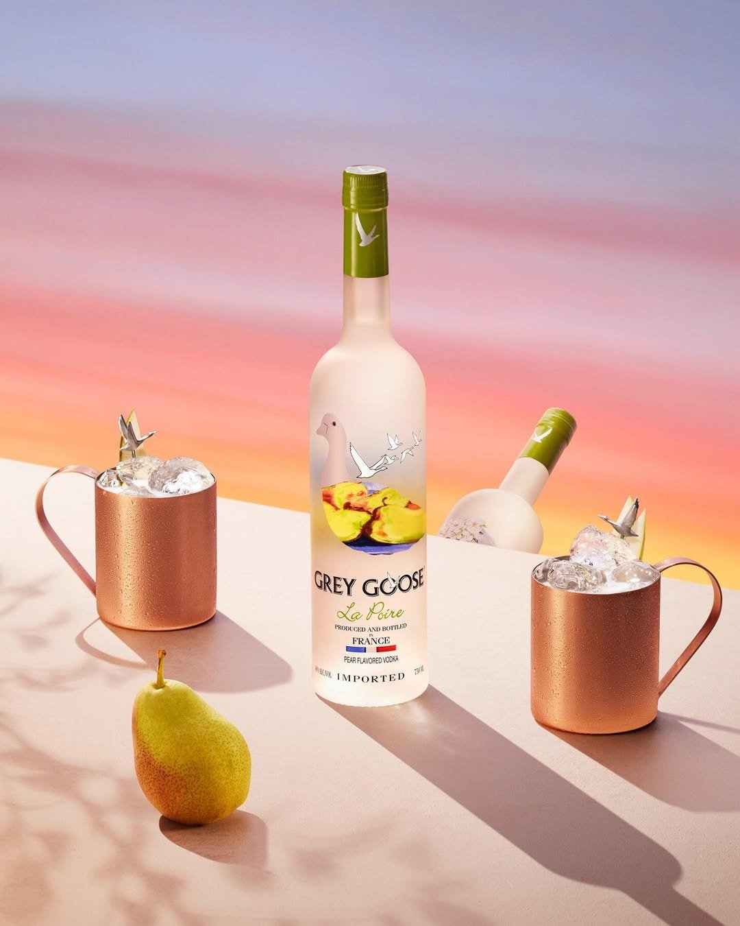 Garrafa de vodka Grey Goose La Poire com rótulo translúcido, copos de cobre com gelo drinks com vodka fáceis