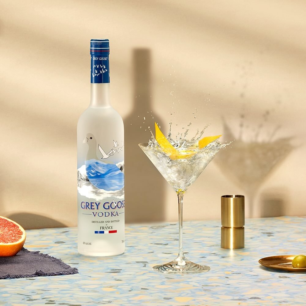 Garrafas de vodka Grey Goose com drink em taça de coquetel, limão siciliano e ambiente claro realçam drinks com vodka fáceis.