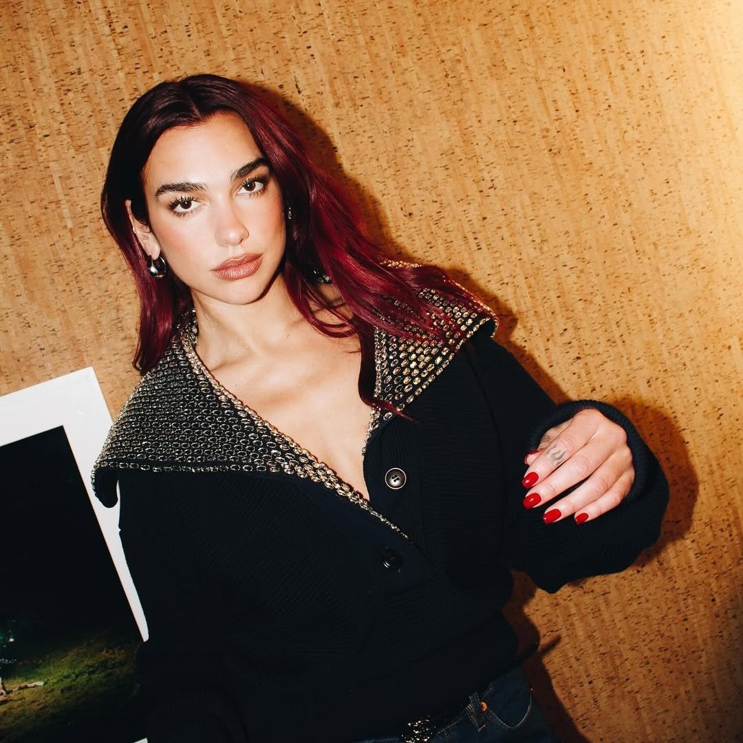 Opções de tinta para cabelo ruivo em visual sofisticado: modelo posa com tricô preto, gola metalizada e fundo amadeirado.