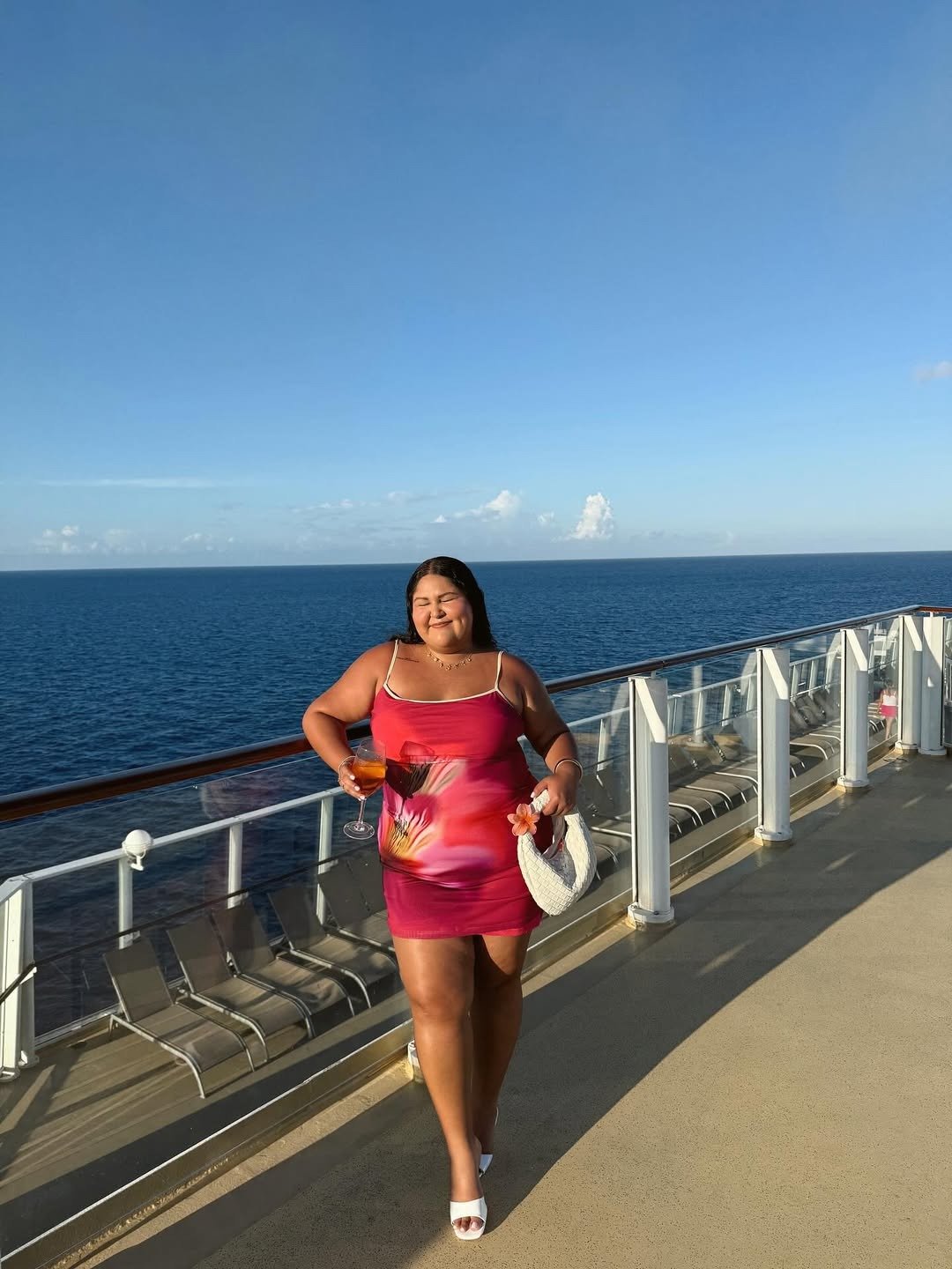 Modelo posa sorrindo com vestido tendência 2026 justo em malha leve rosa com estampa floral, clima alegre e verão à